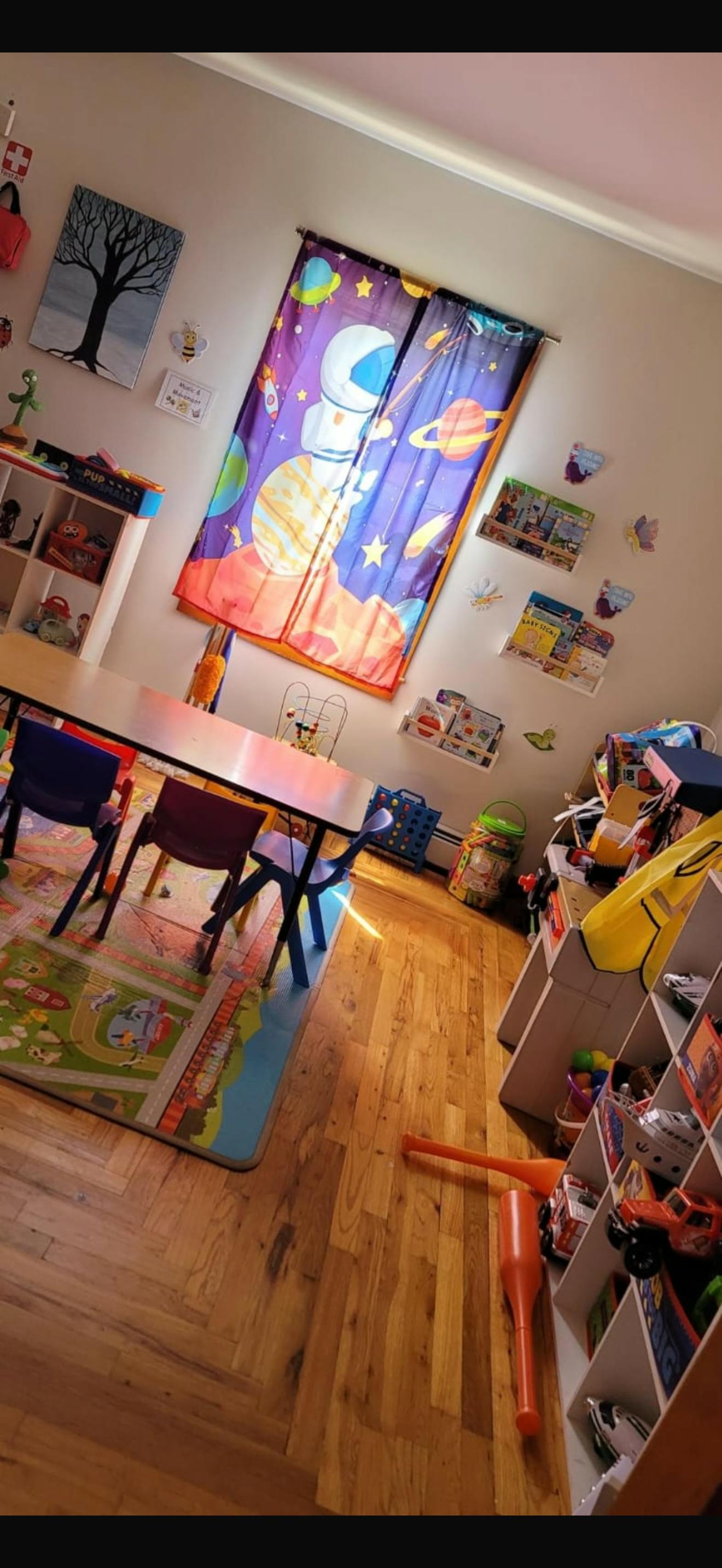 A classroom with a table, chairs, and space-themed curtains