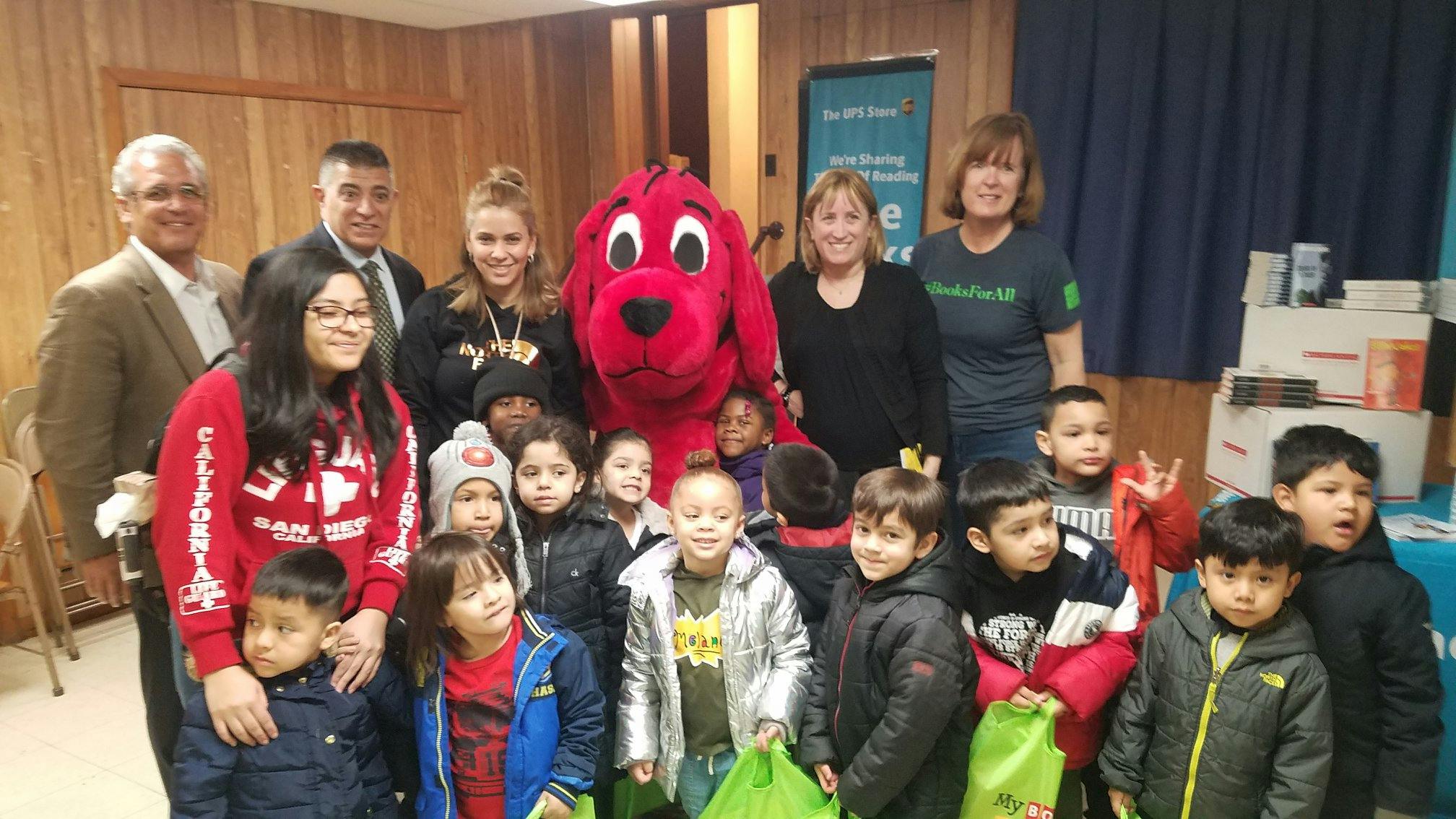 Adults and children posing with a person in a red dog costume