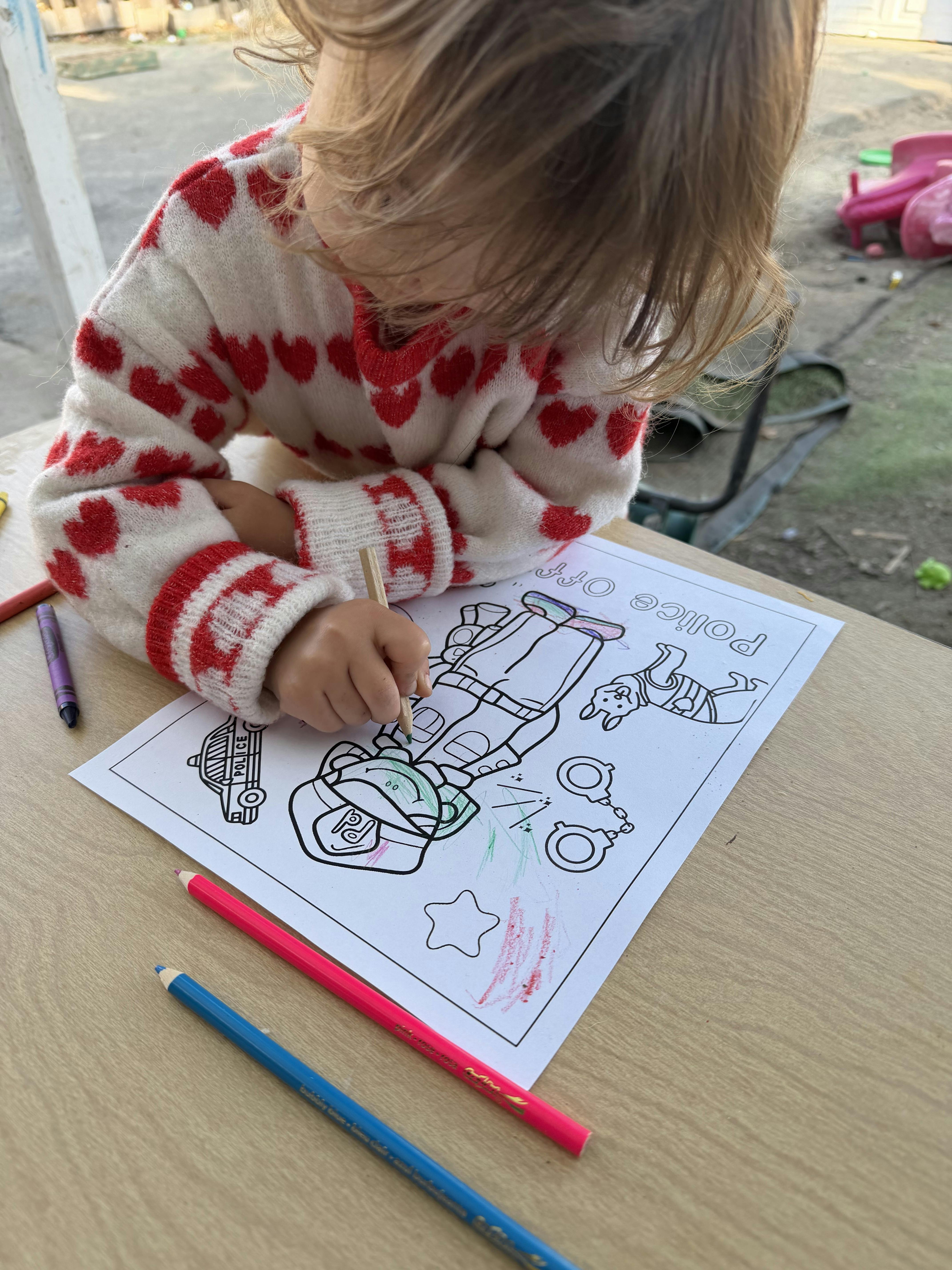 Child coloring a police-themed activity sheet at a table