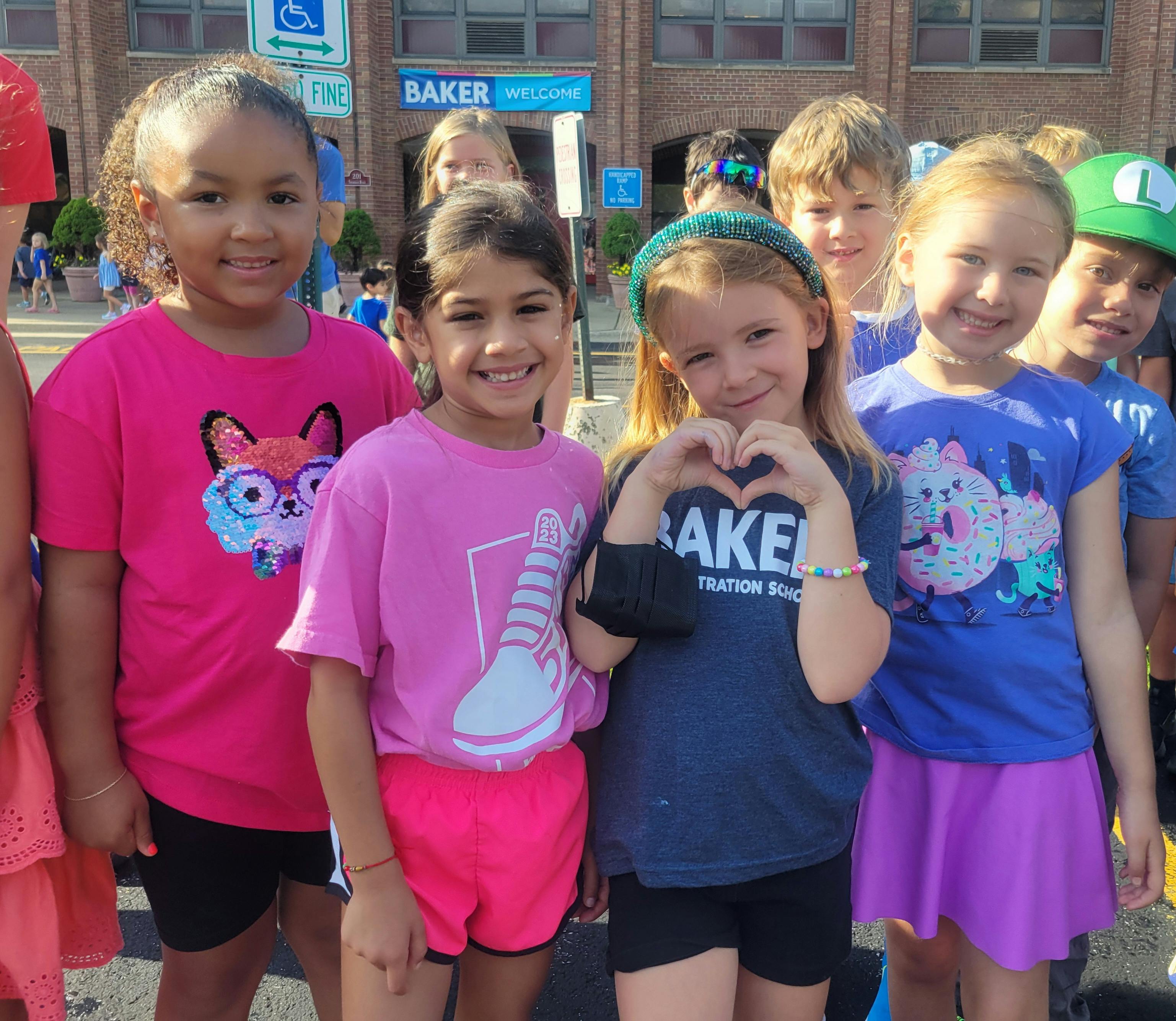Group of children smiling, one child making a heart shape with hands