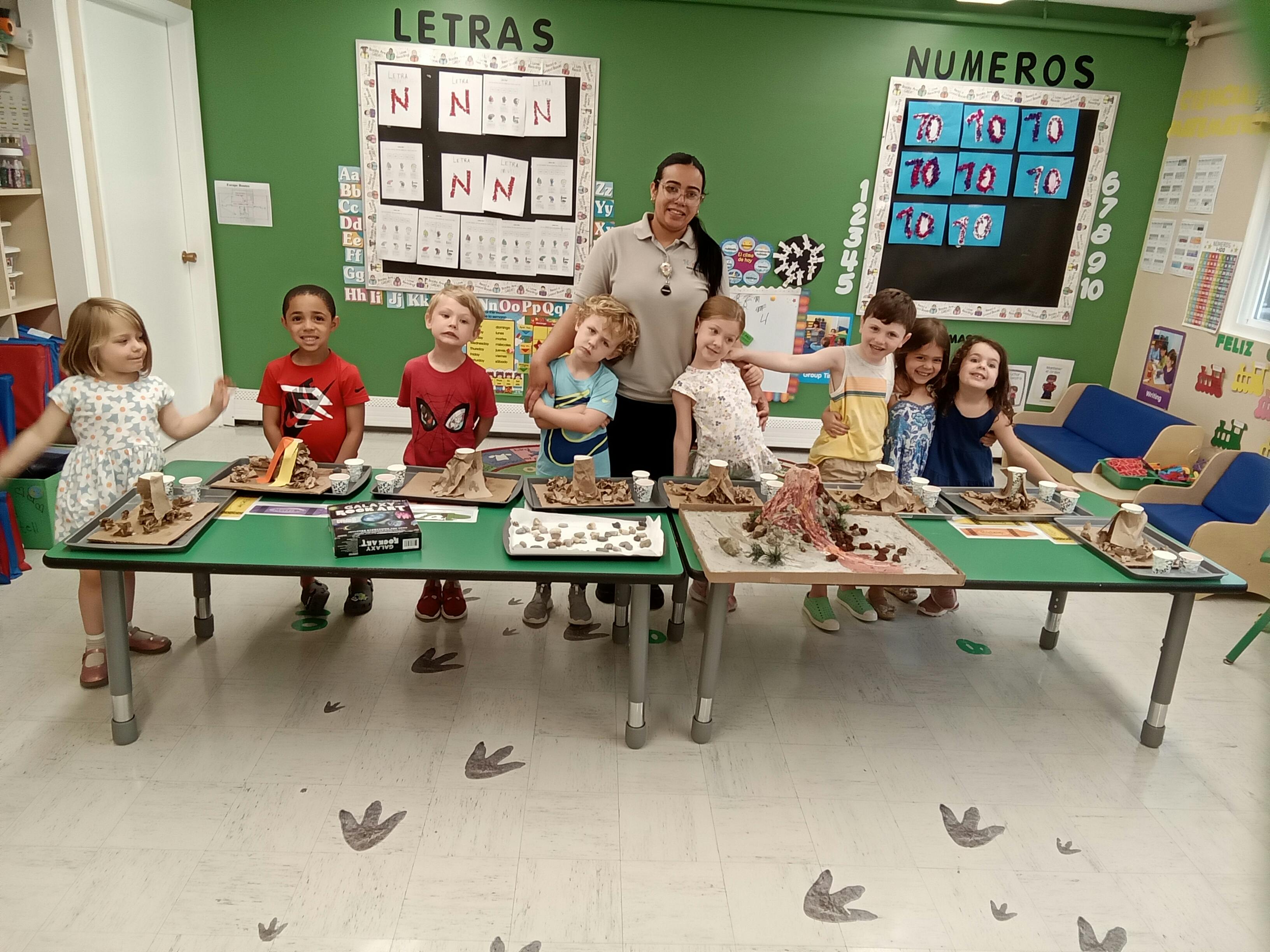 Adult and children standing behind tables with craft projects in a classroom