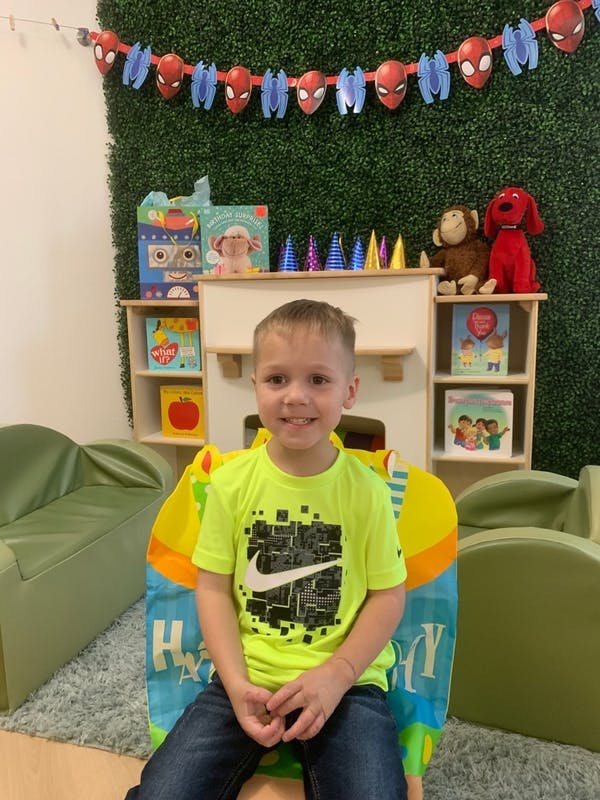 Child sitting in a chair in front of a decorated wall