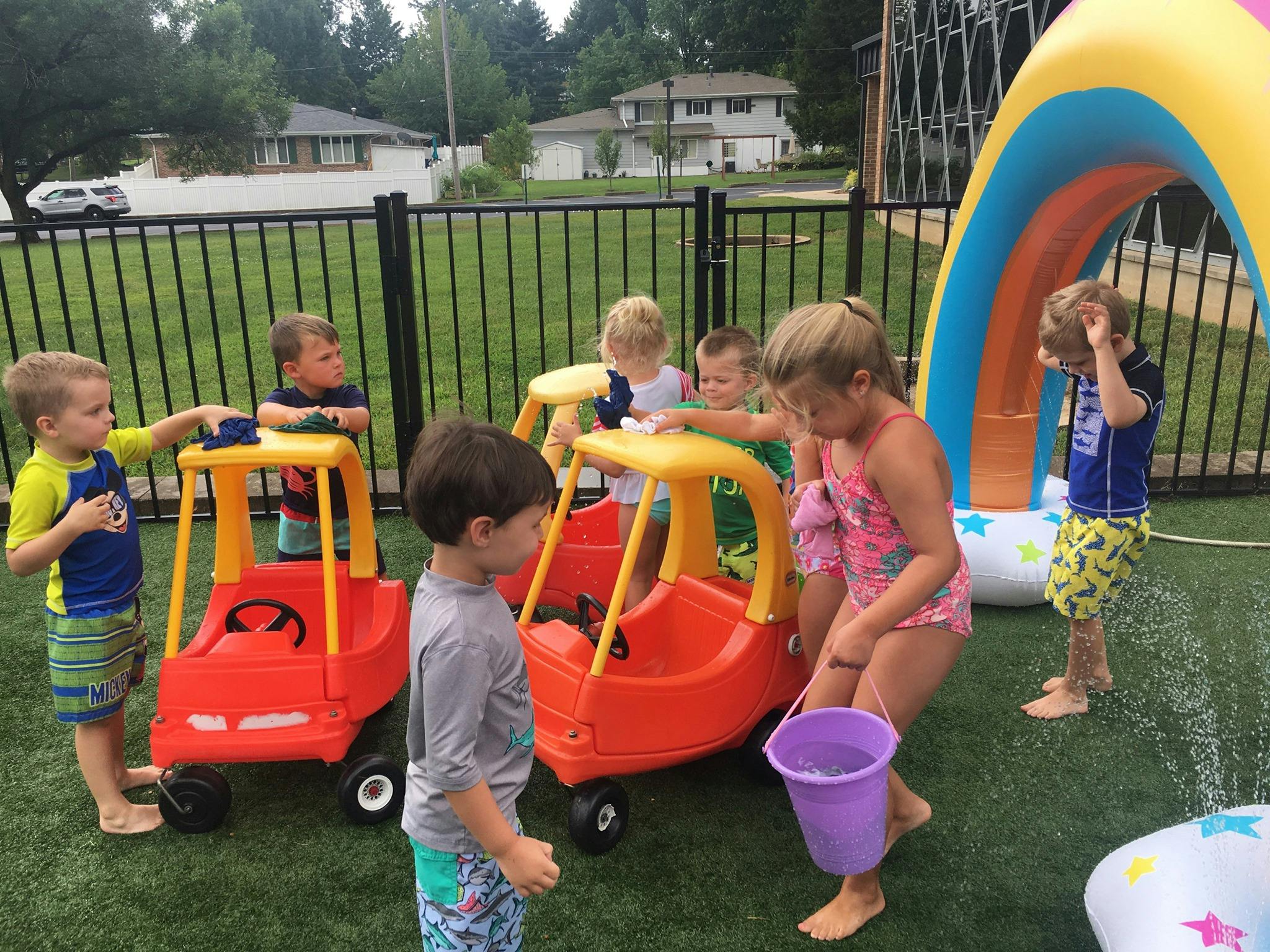 Children playing with toy cars and water outdoors