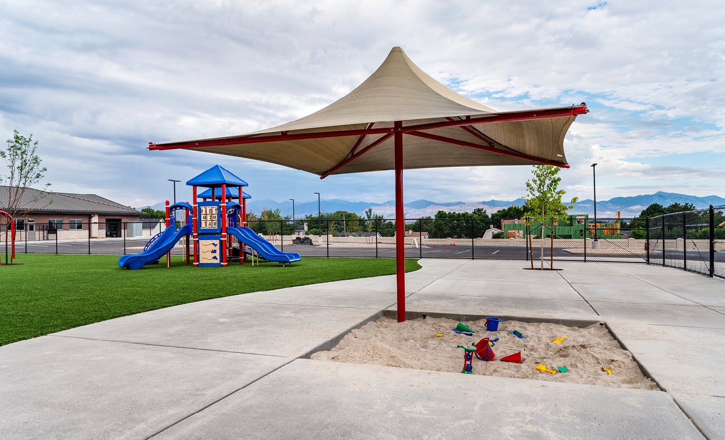Sandbox under a shade structure next to a playground