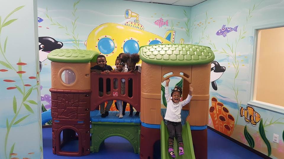 Child on a slide with other children on a play structure