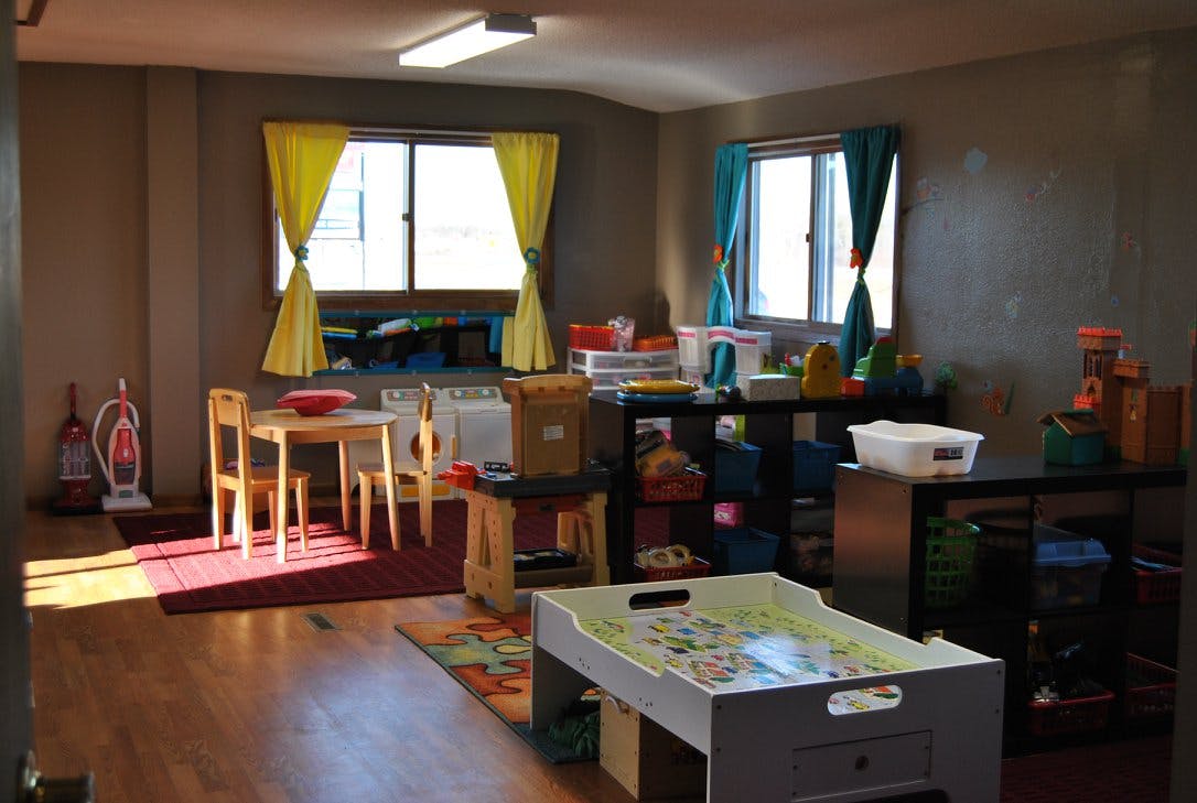 Classroom with small tables and chairs, storage shelves, and windows