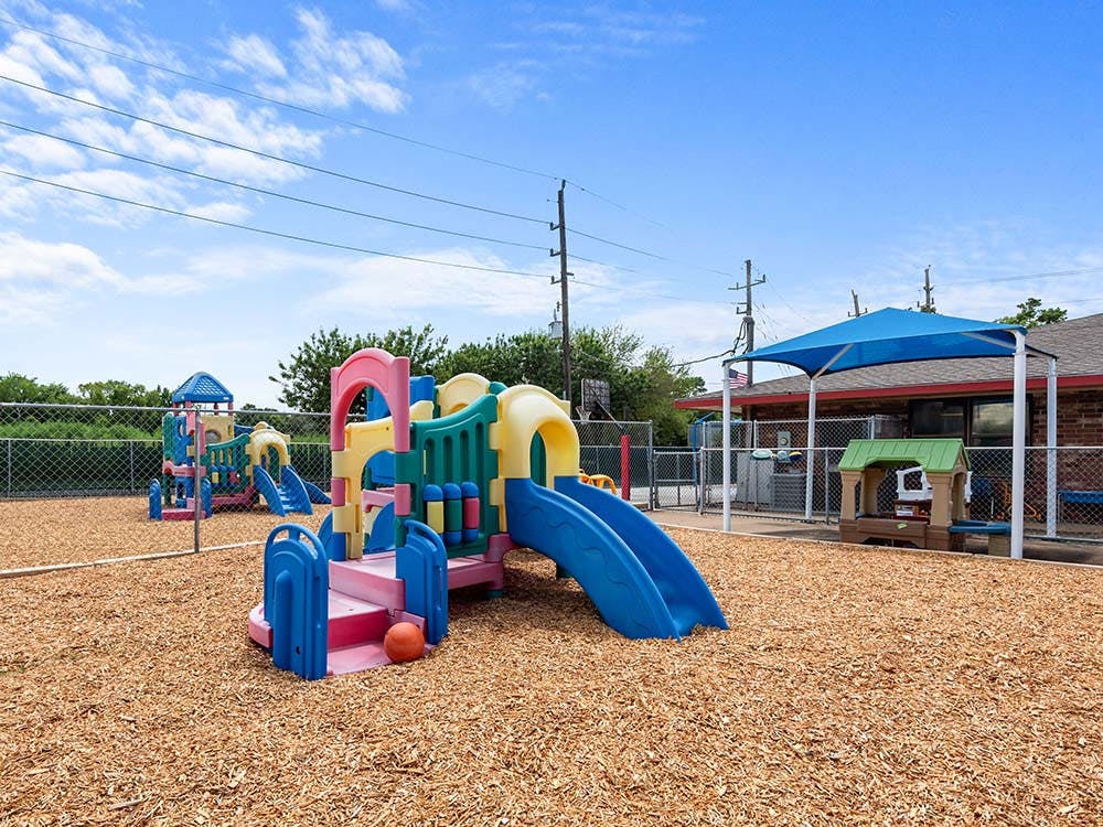 Colorful playground equipment on wood chips under a blue sky