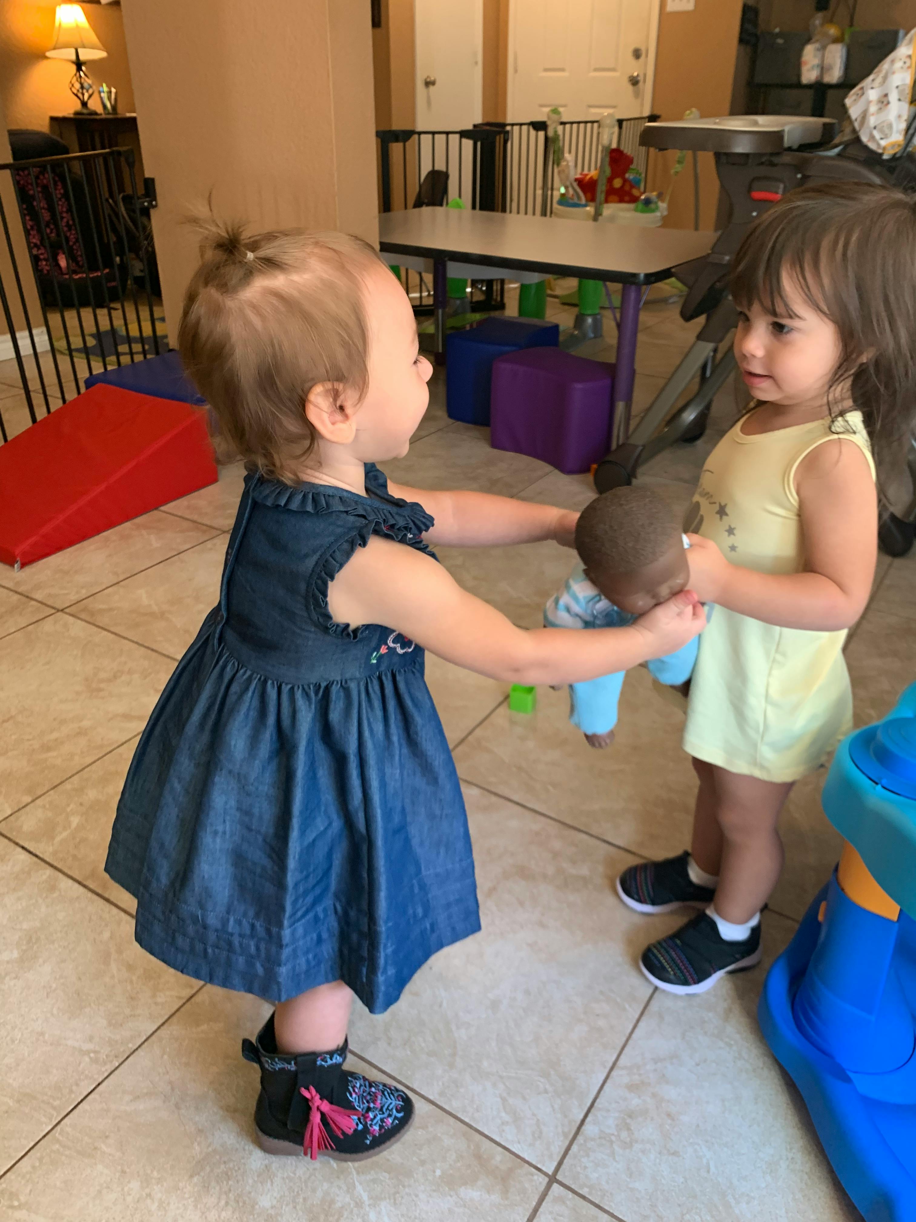 Two children playing with a doll