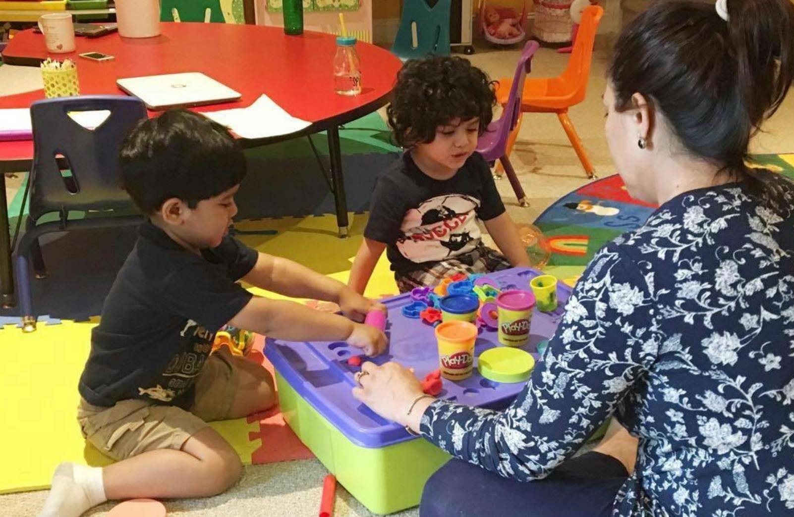 Adult and two children playing with modeling clay at a table