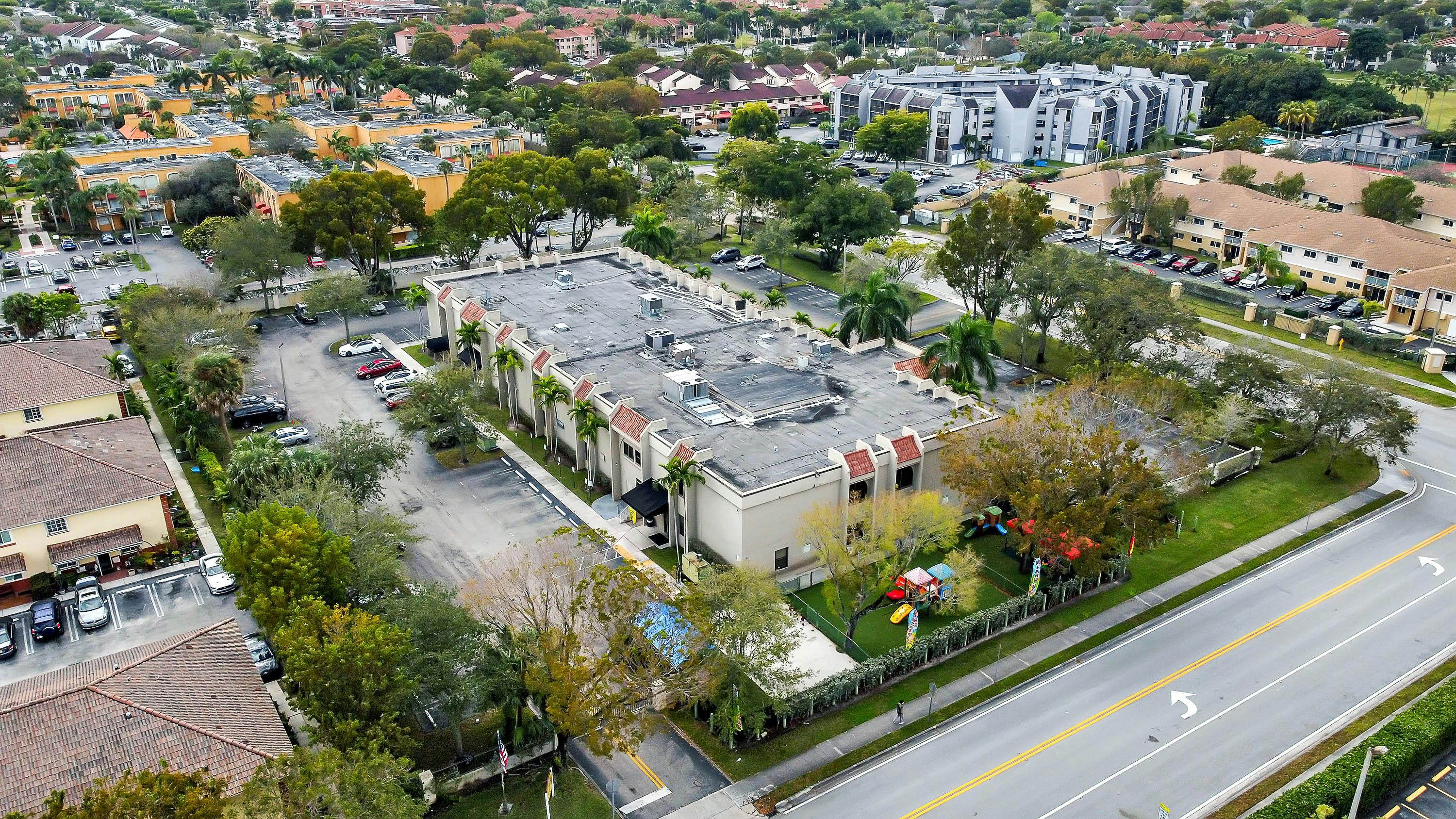 Aerial view of a building with a parking lot and adjacent road