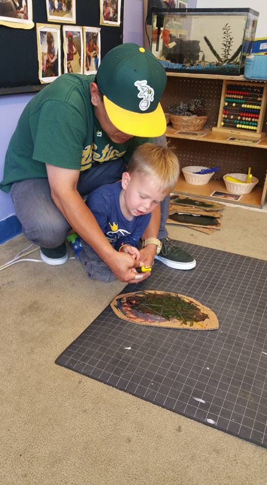 Person and child on floor doing an activity with leaves