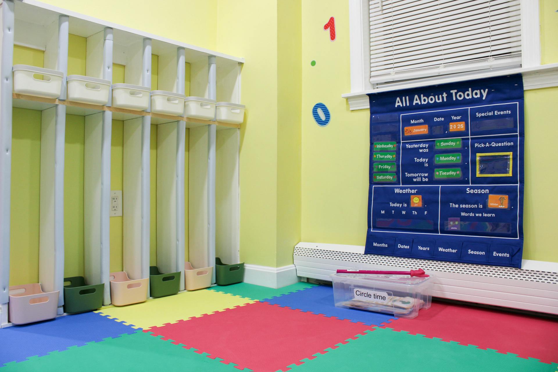 Classroom with cubbies, a calendar chart, and colorful floor mats