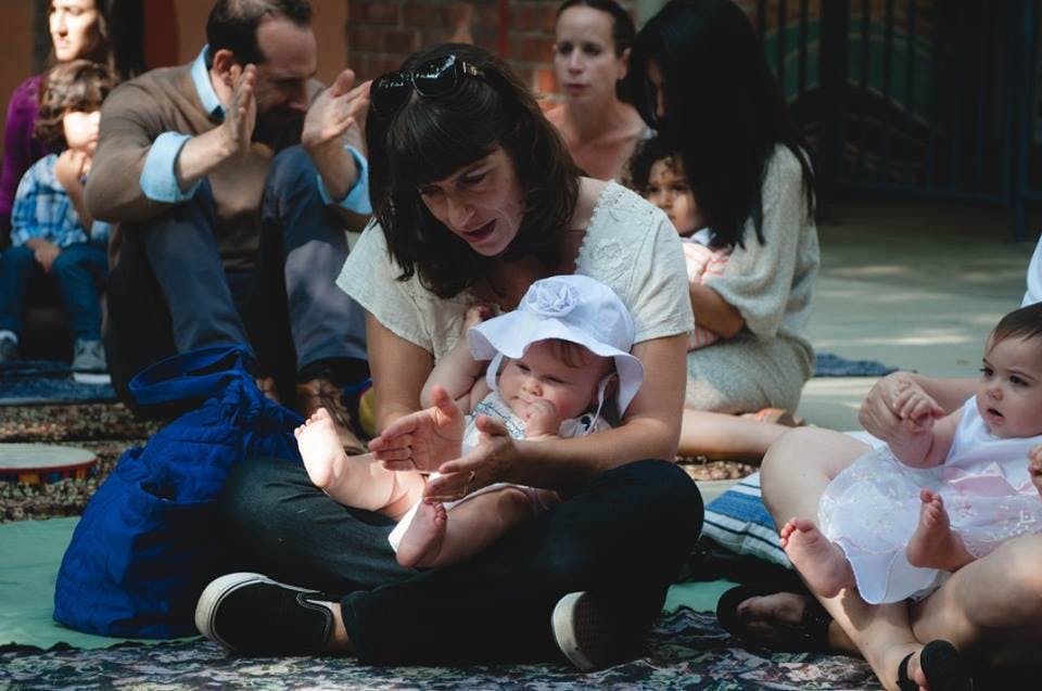 Person holding a child in a white hat, another child nearby