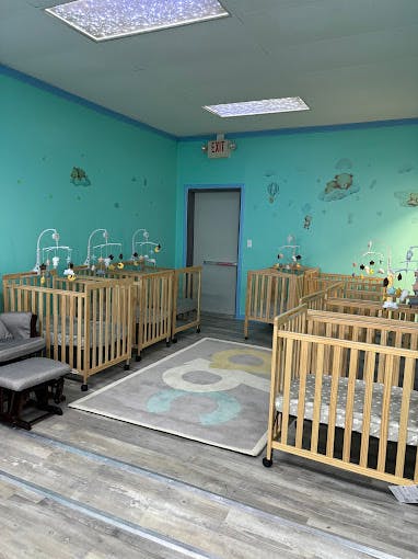 Room with multiple cribs and a rocking chair