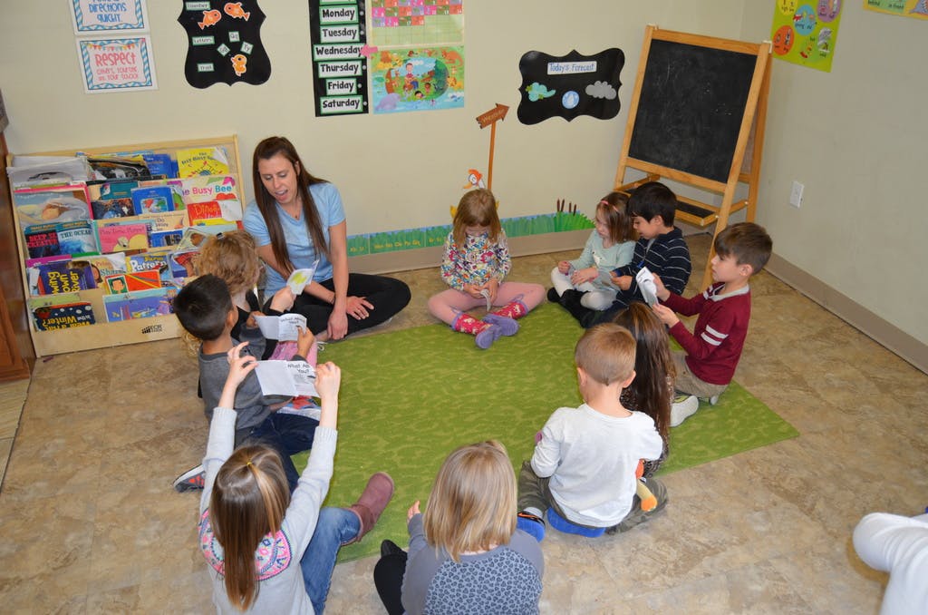 Adult and children sitting on a rug in a classroom