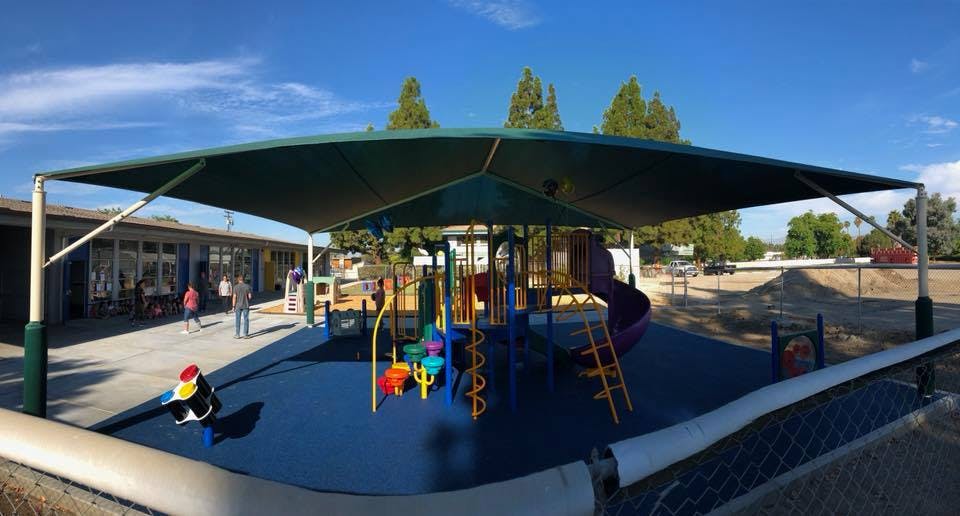 Playground with shade structure and building in background