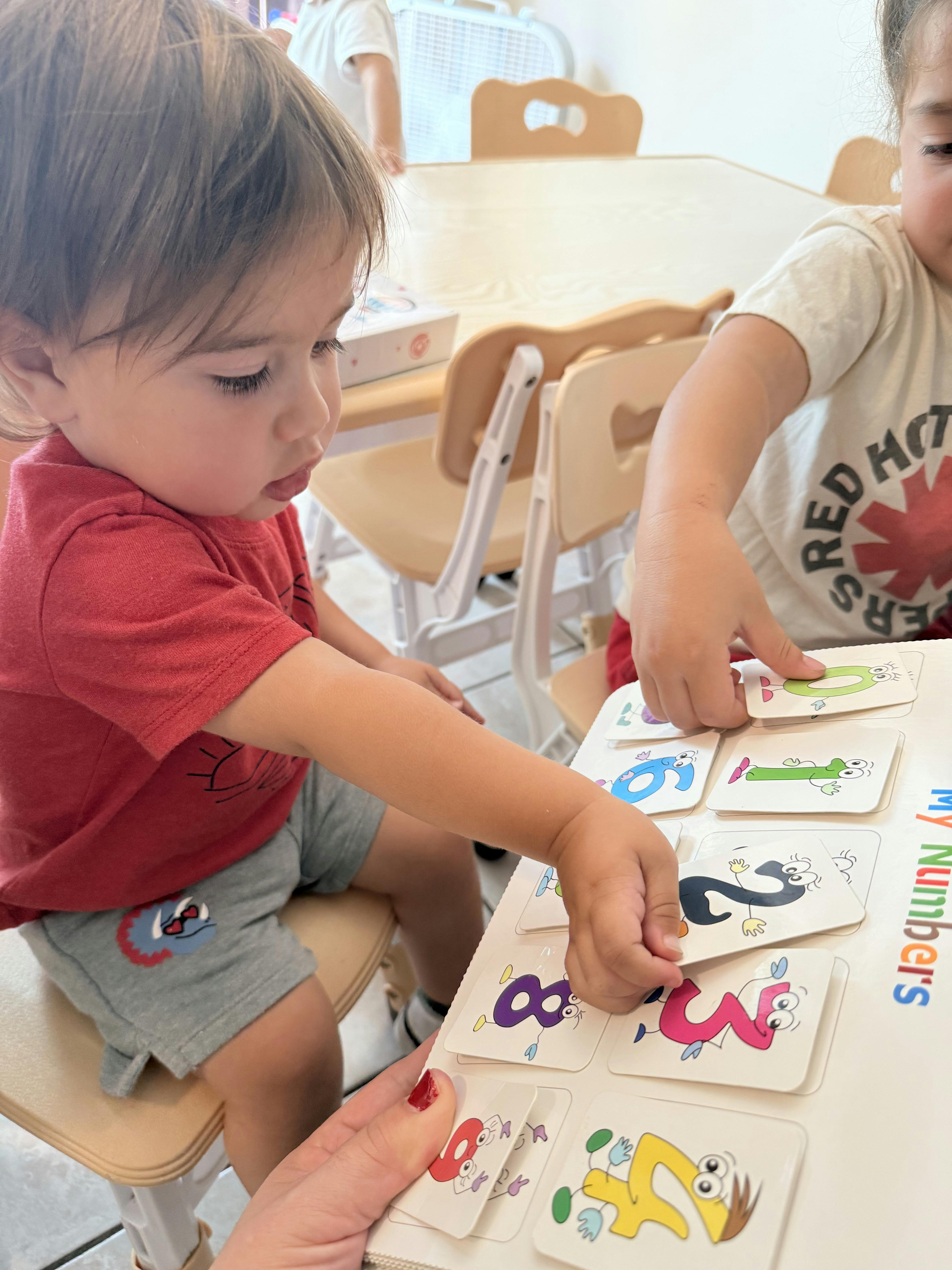 Two children playing with number cards in a classroom