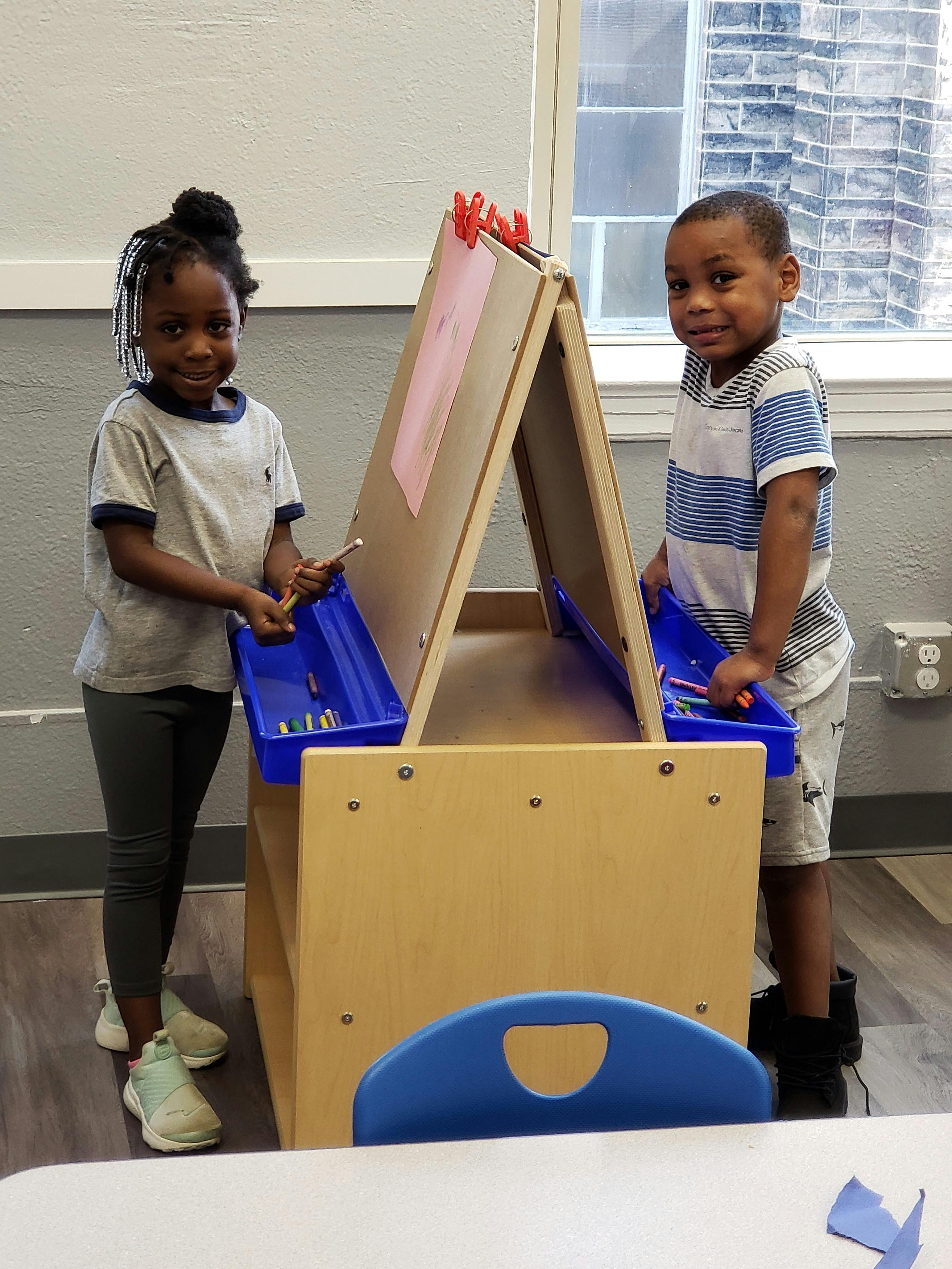 Two children standing at an easel