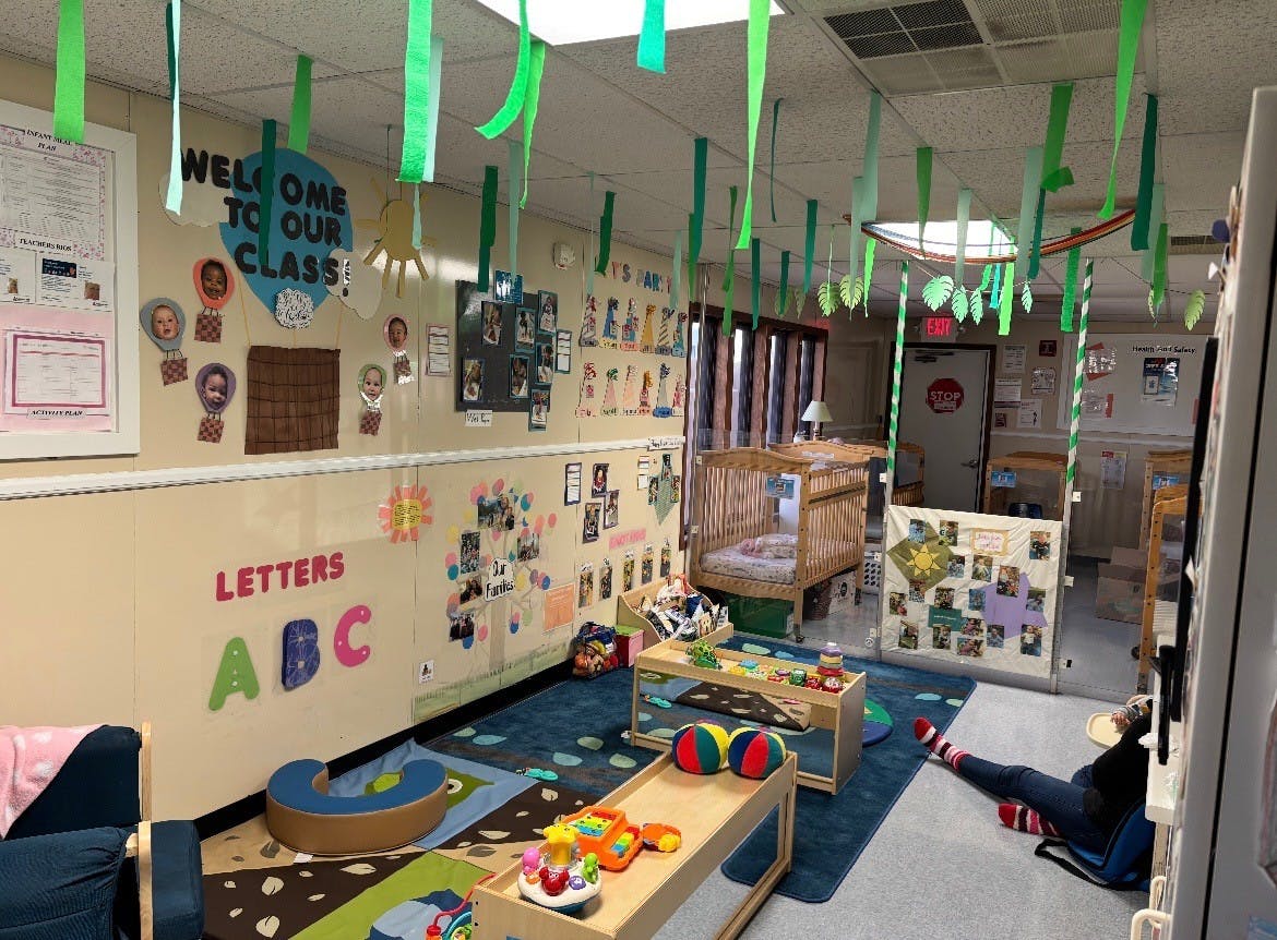 Classroom decorated with paper streamers, cribs, and child-related art