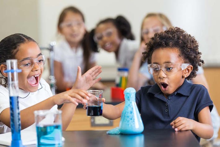 Children in safety glasses doing a science experiment with beakers
