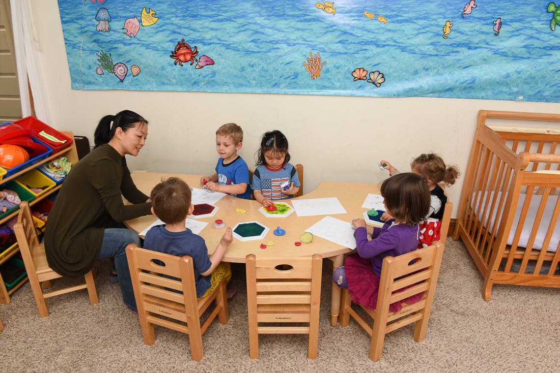 Adult and children sitting at a table with papers and colorful items