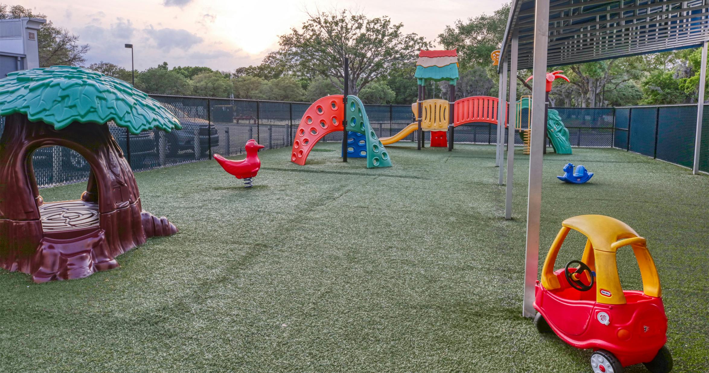 Empty outdoor playground with colorful play structures and artificial turf