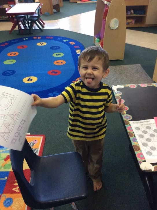 Child holding a paper in a classroom