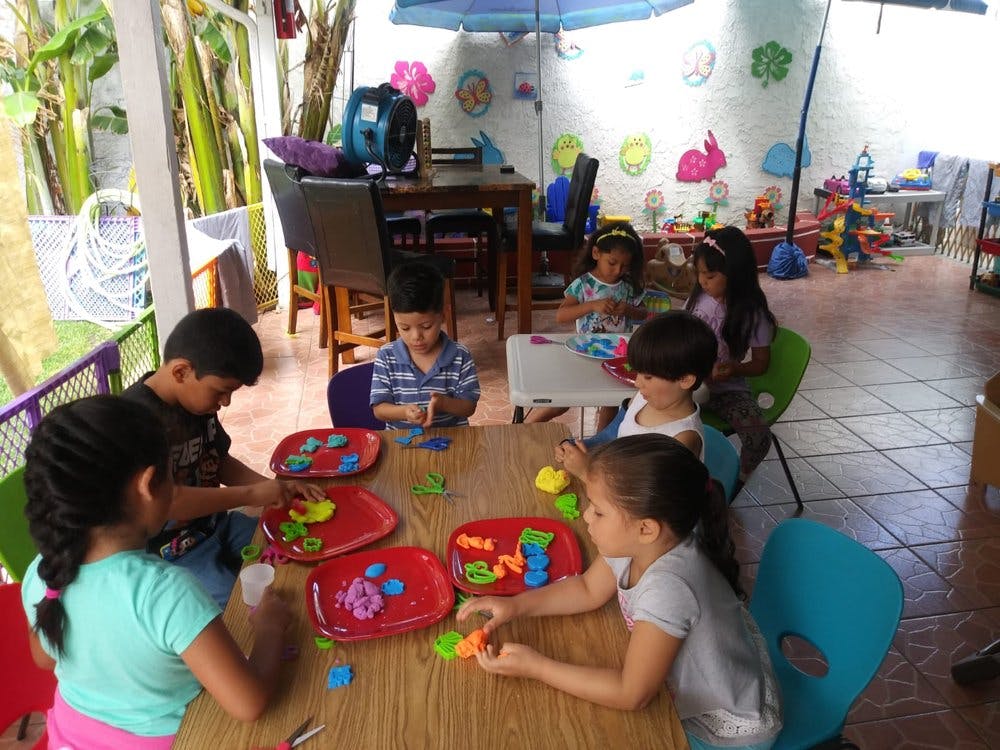 Children playing with colorful toys at a table in a classroom