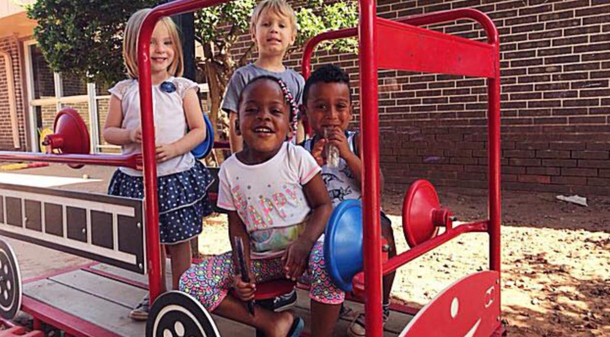 Children playing on a red toy fire truck