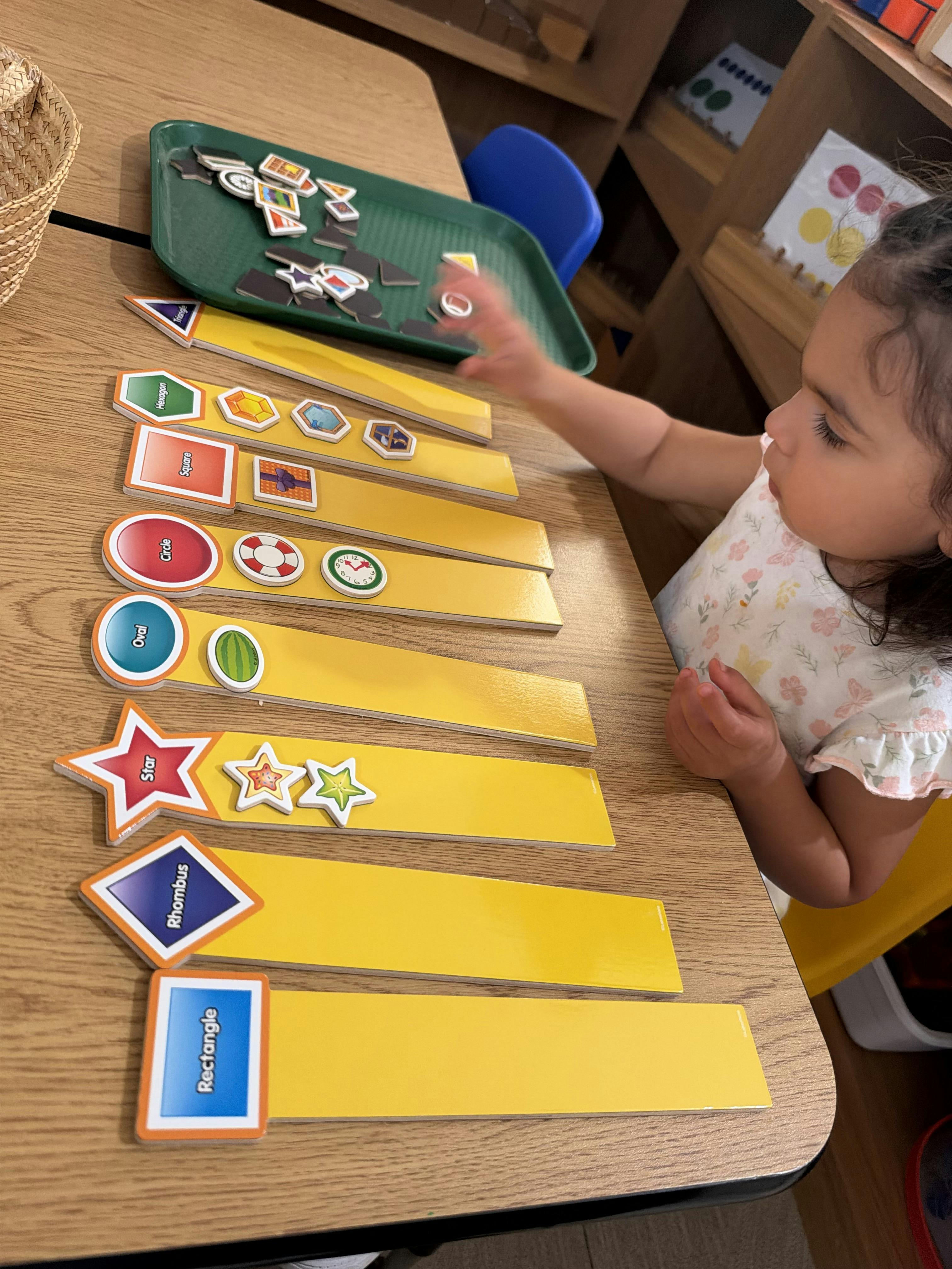 Child placing shape tiles onto wooden game strips on a table