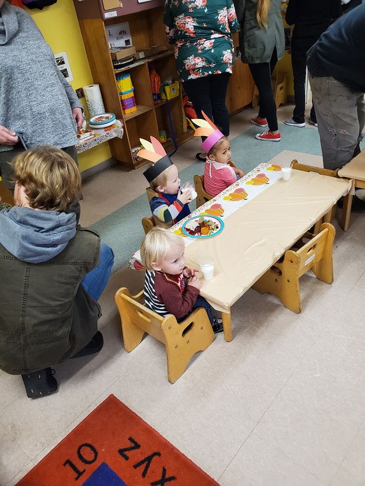 Children wearing paper crowns sitting at a table in a classroom
