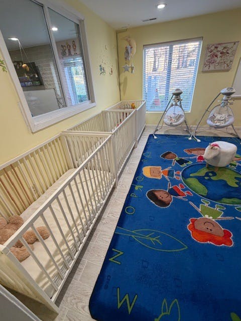 Cribs and baby swings in a room with a blue rug and yellow walls