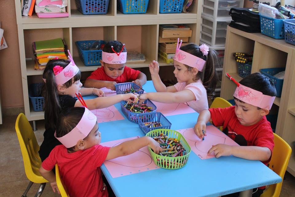 Children at a table with baskets of crayons