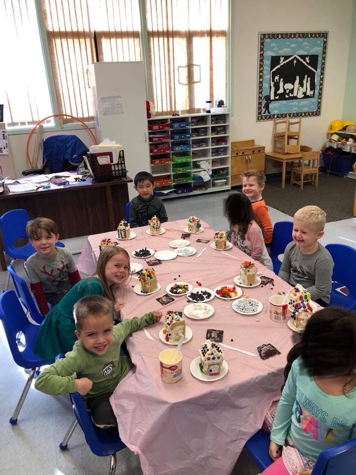 Children sitting at a table with cupcakes and toppings
