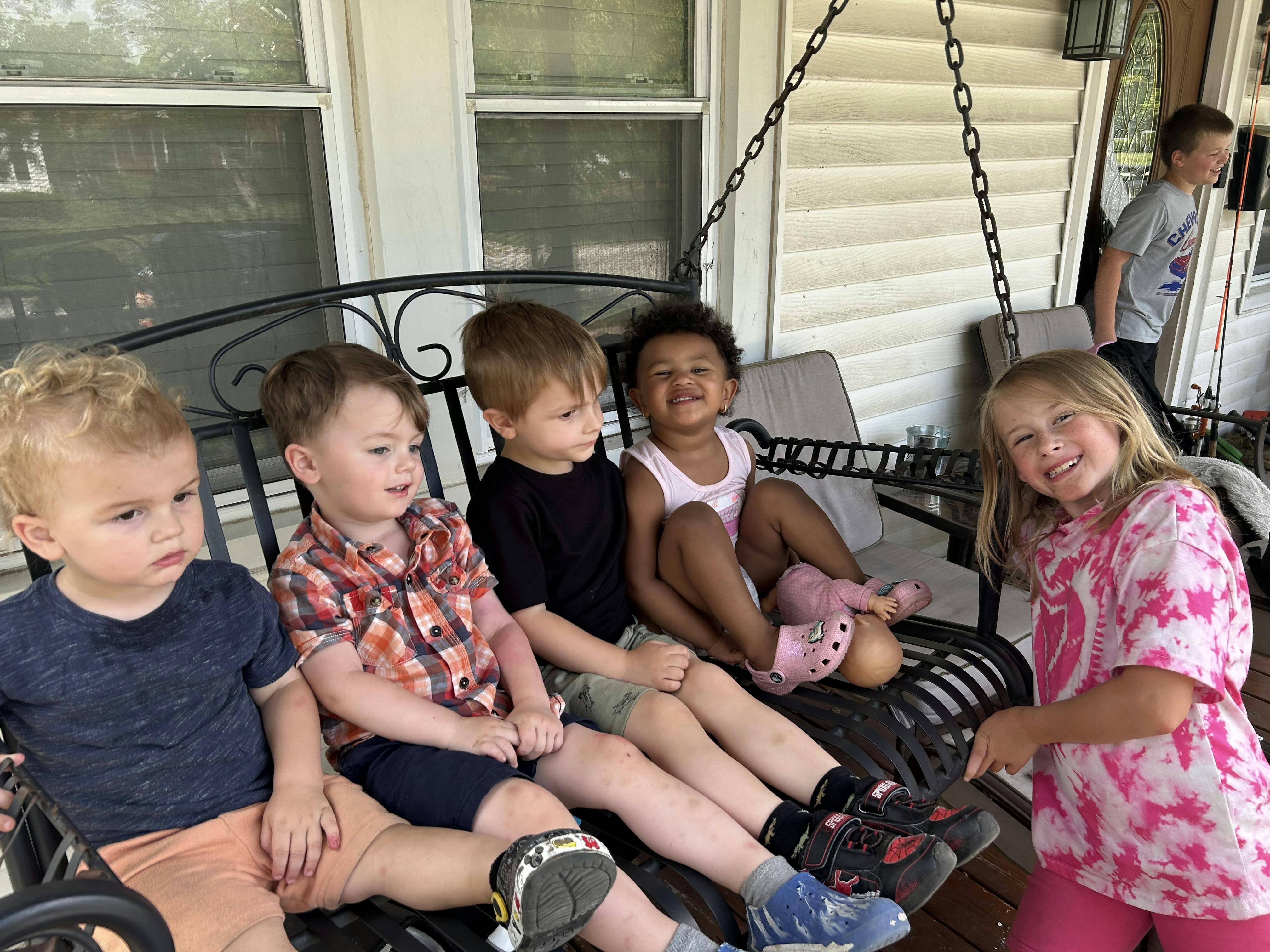 Five children sitting on a porch swing