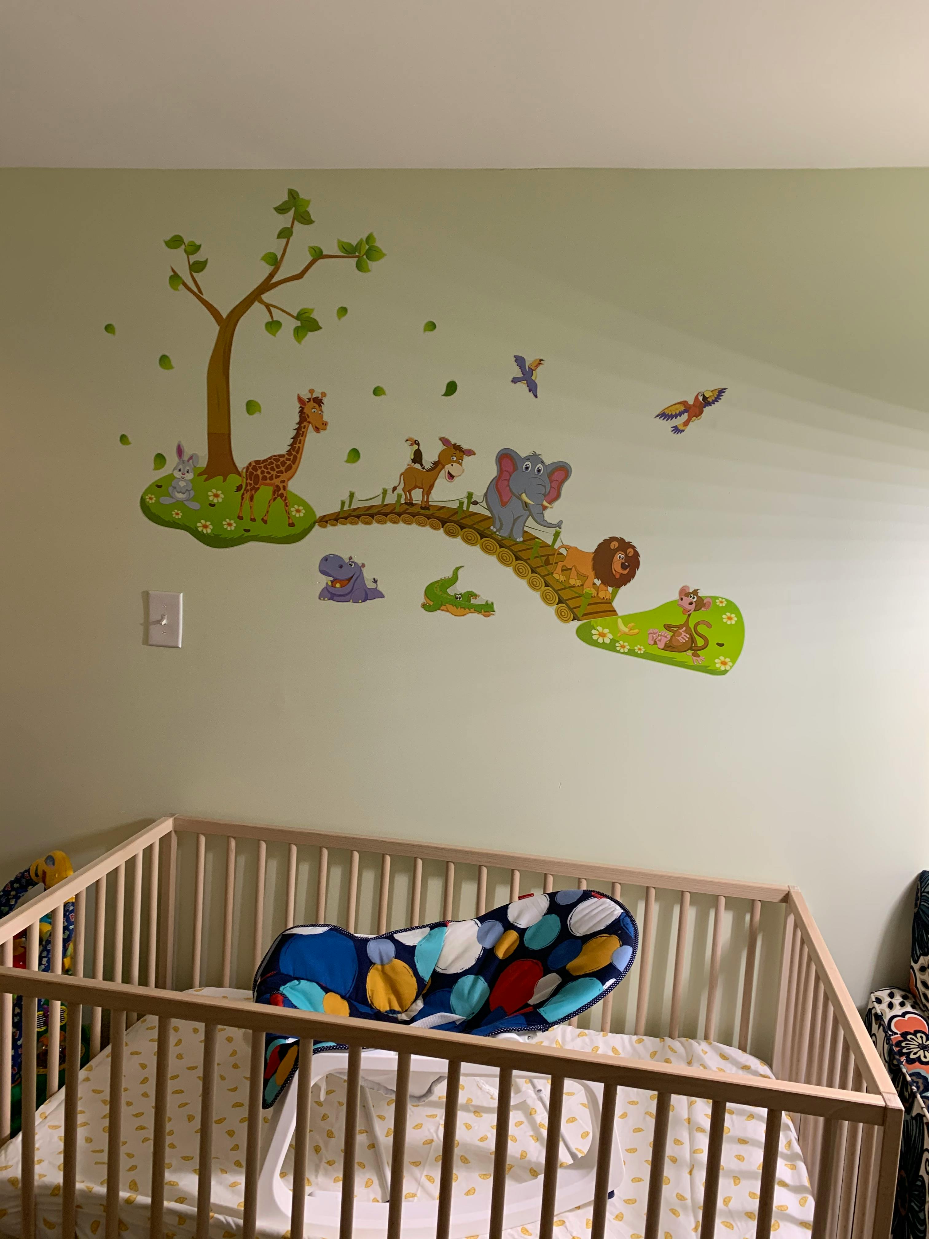 Nursery with a crib and wall decals of cartoon animals and a tree