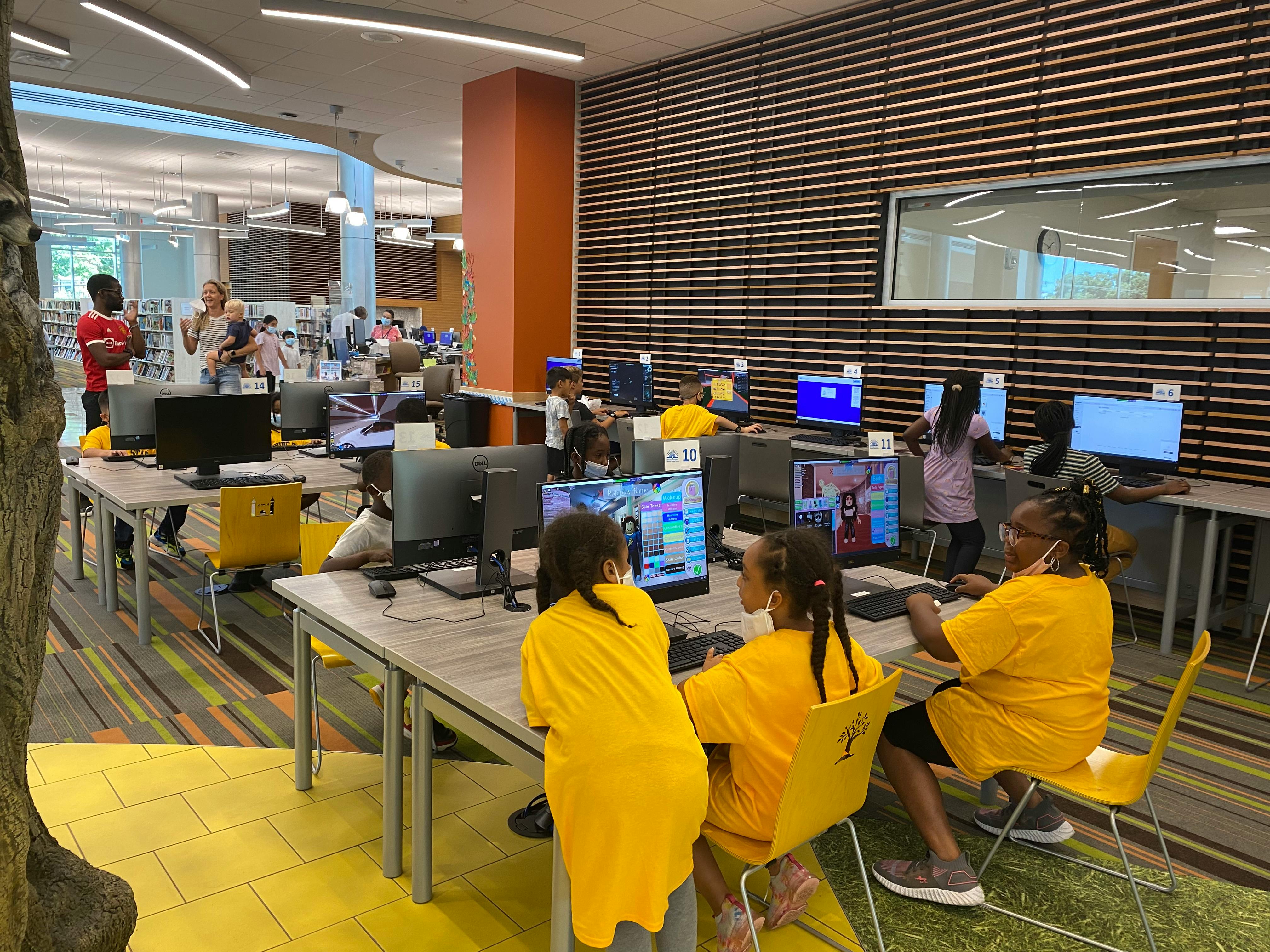 Children and adults using computers in a room