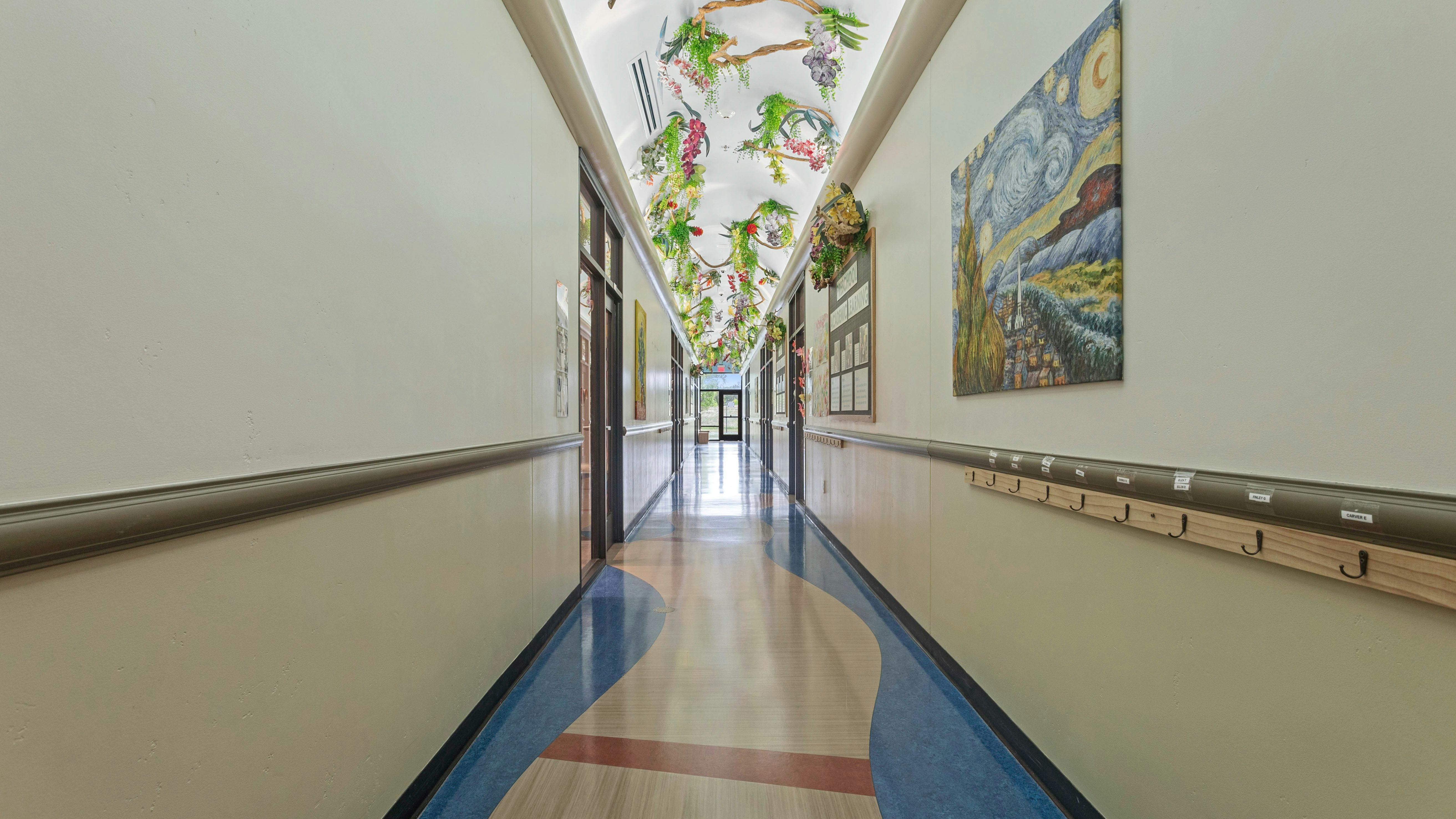 A long, brightly lit school hallway with abstract blue and tan flooring