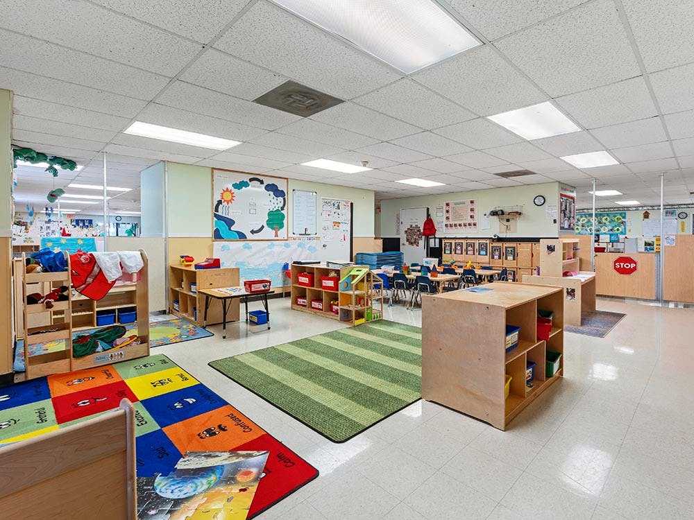 Empty classroom with colorful rugs and small chairs