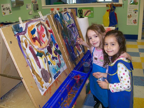 Two children painting at easels in a classroom