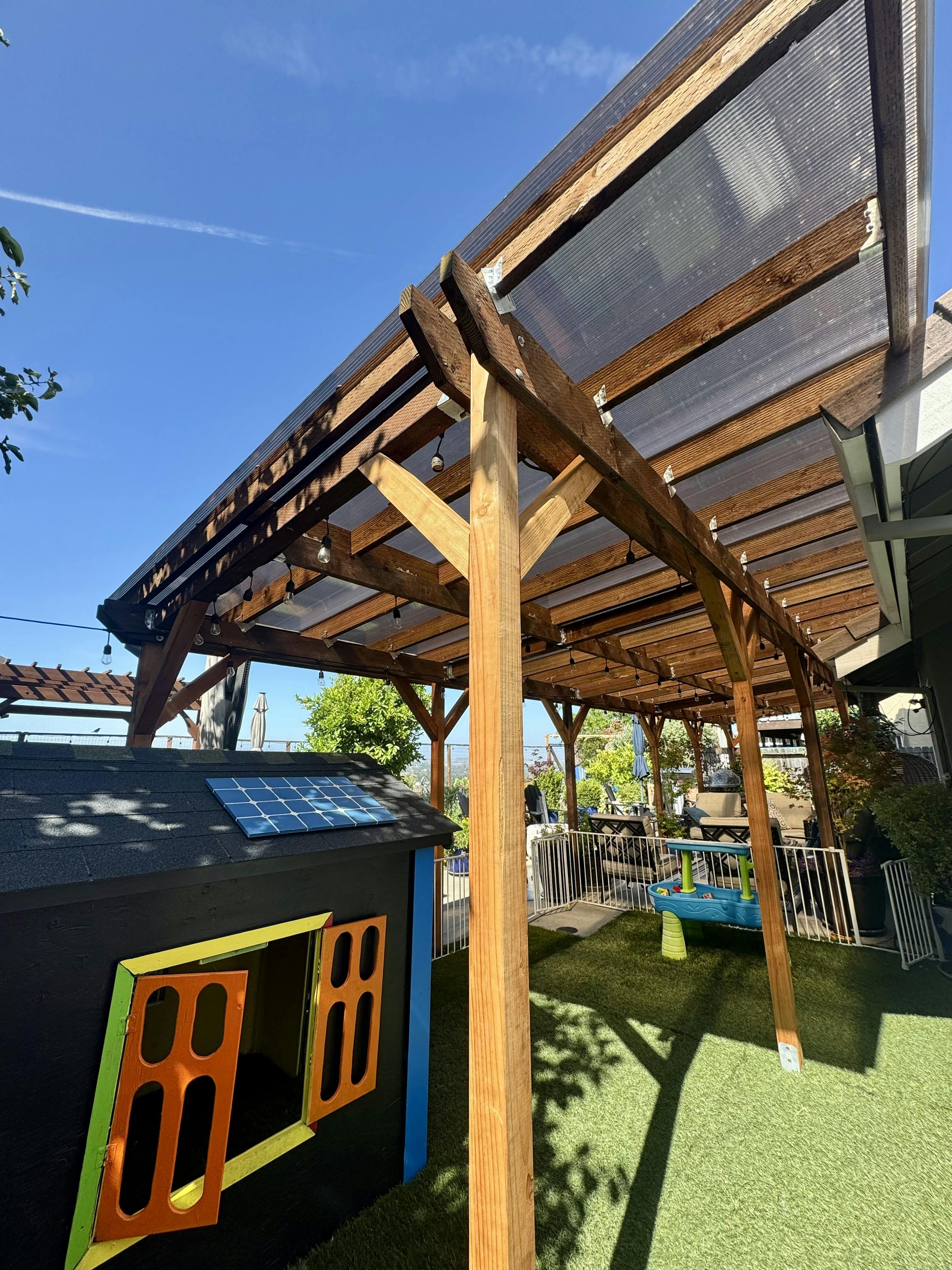 Outdoor play area with a wooden pergola and a small playhouse