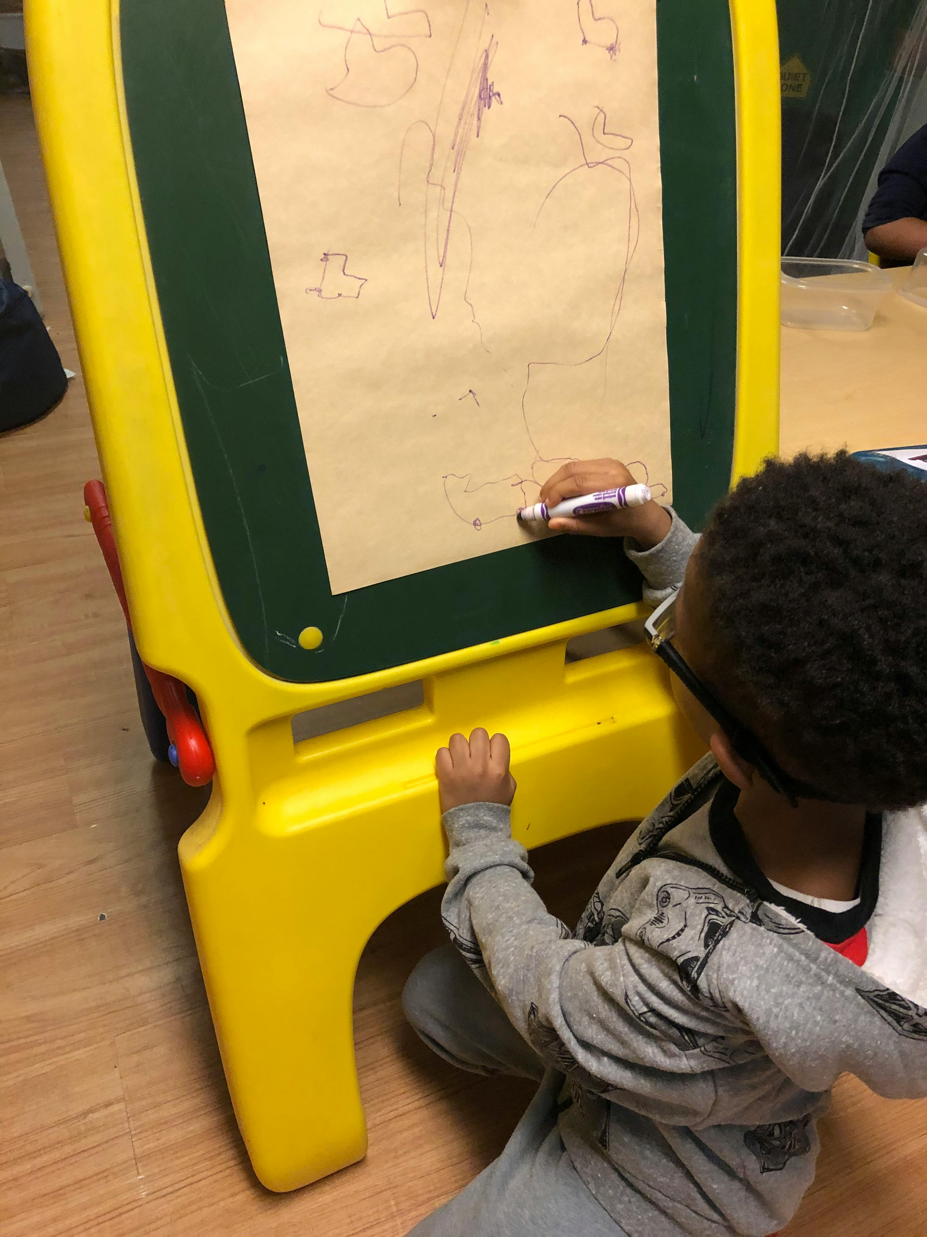 Child drawing on an easel with a marker