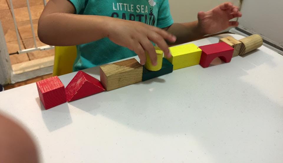 Child playing with colorful wooden blocks on a white surface