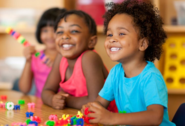 Three children at a table with colorful building blocks