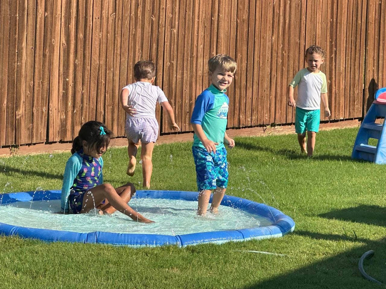 Children playing in a small inflatable pool in a grassy yard