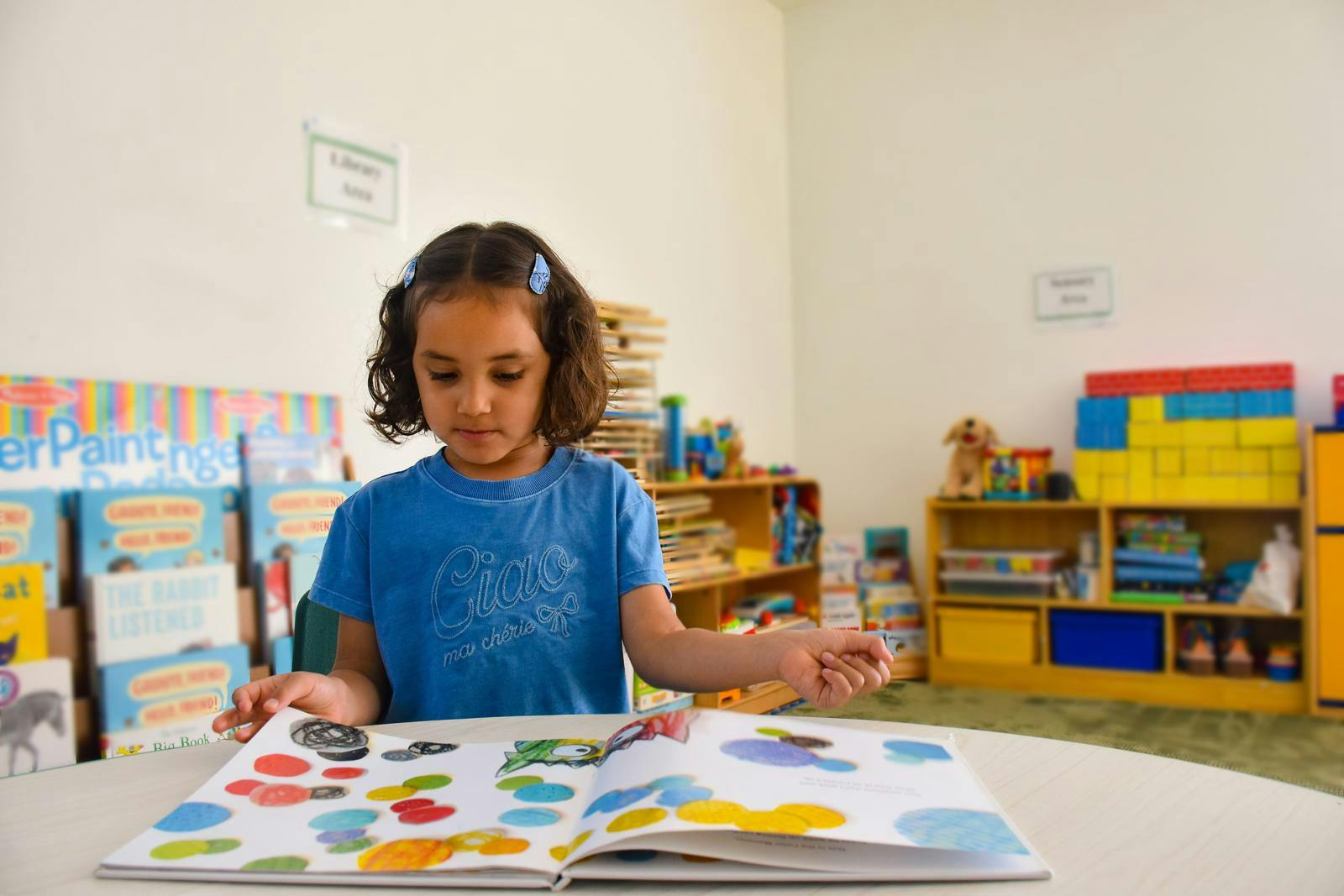 Child reading a picture book in a library area