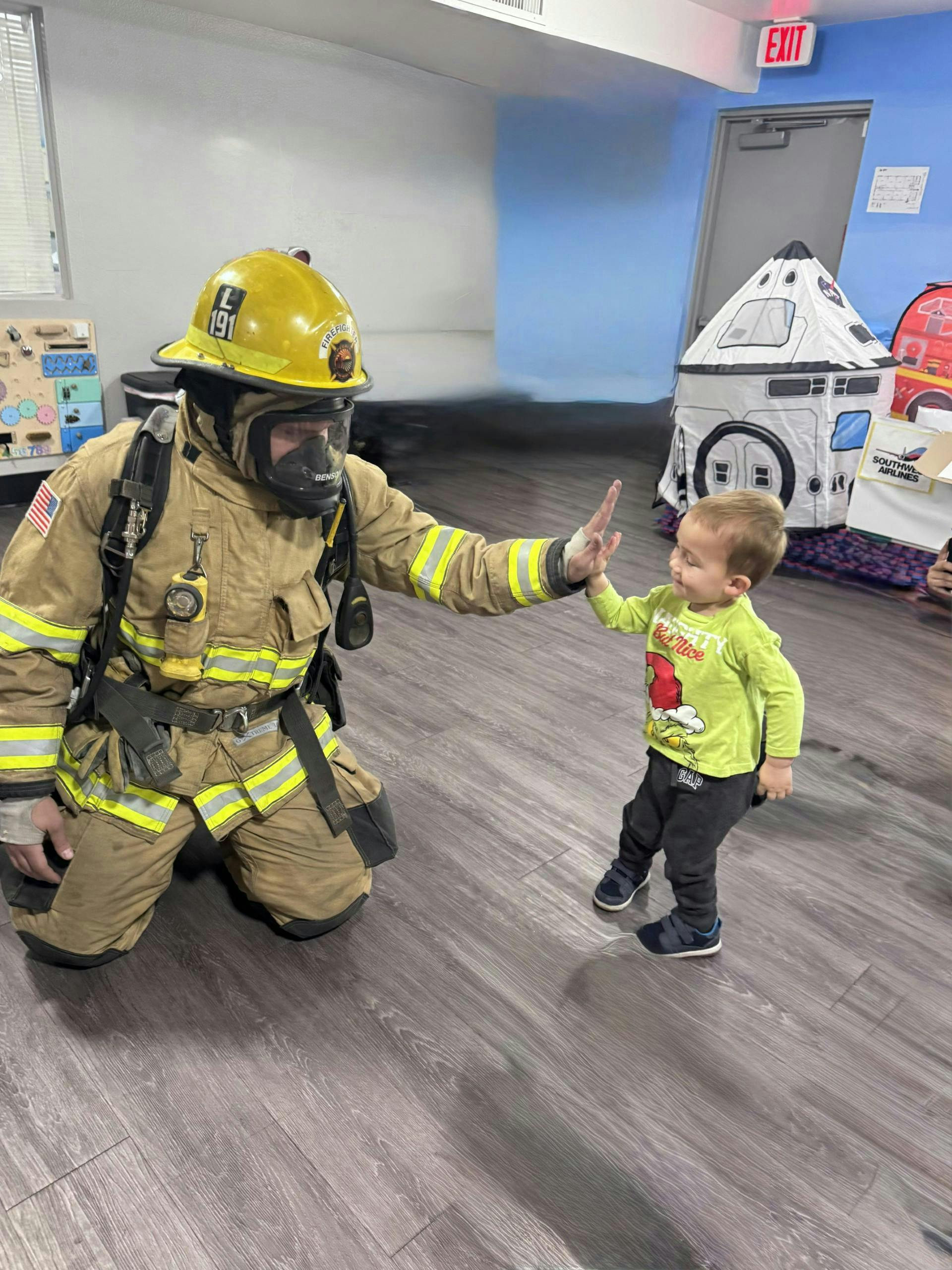 Firefighter in full gear giving a high-five to a child