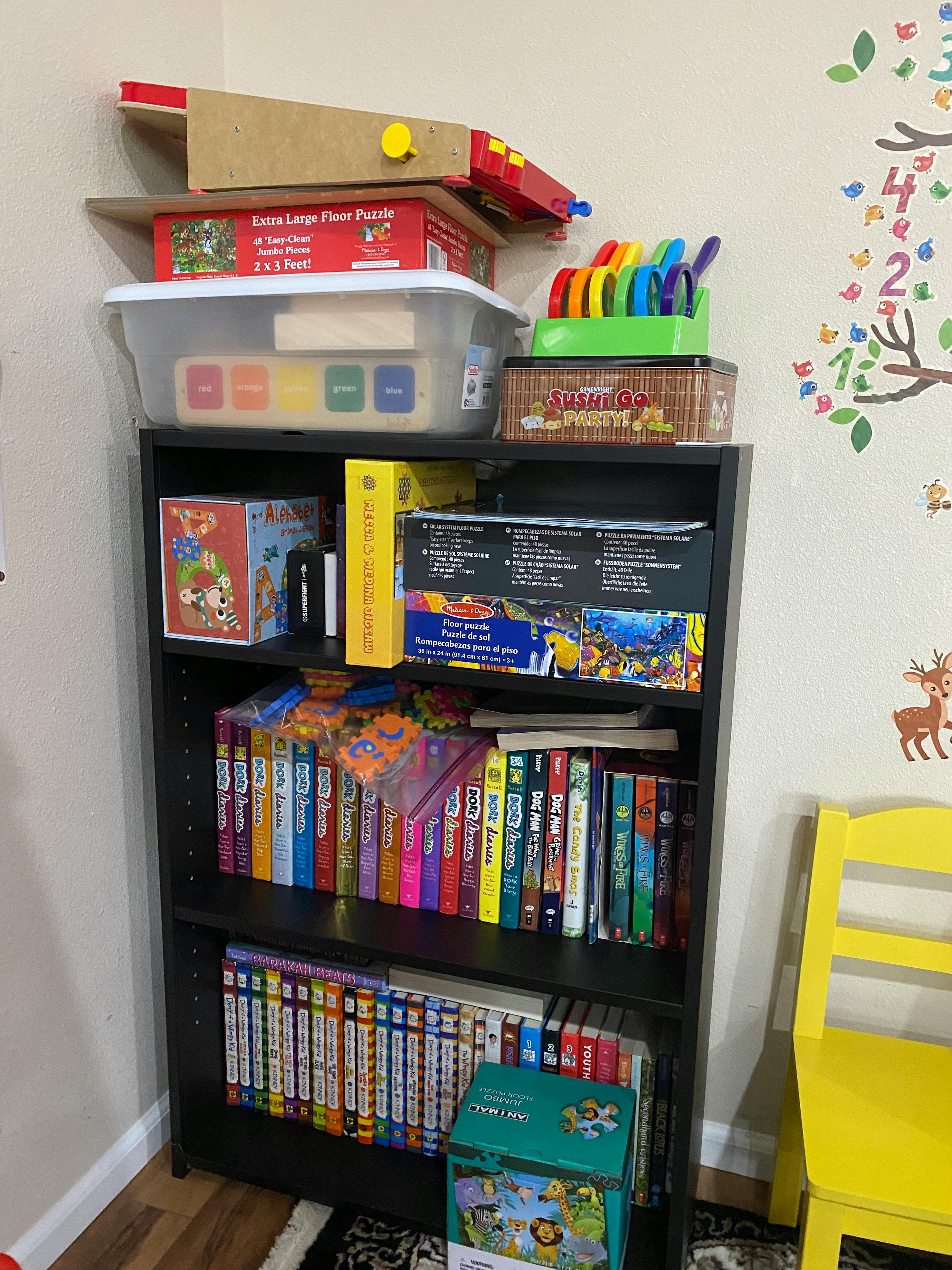 Black bookshelf filled with books, puzzles, and games