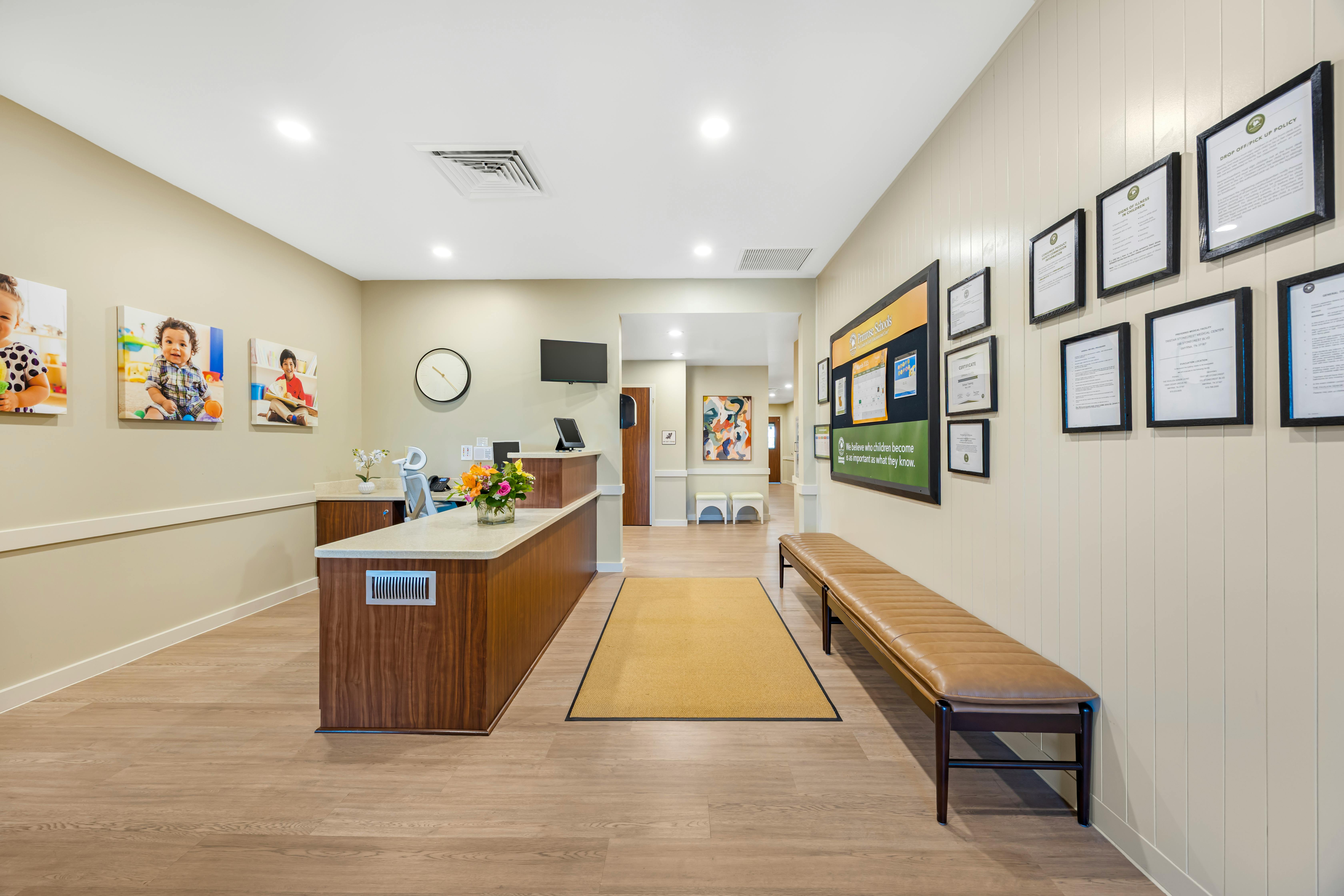 Reception desk with floral arrangement, wall display, and long bench in a waiting area