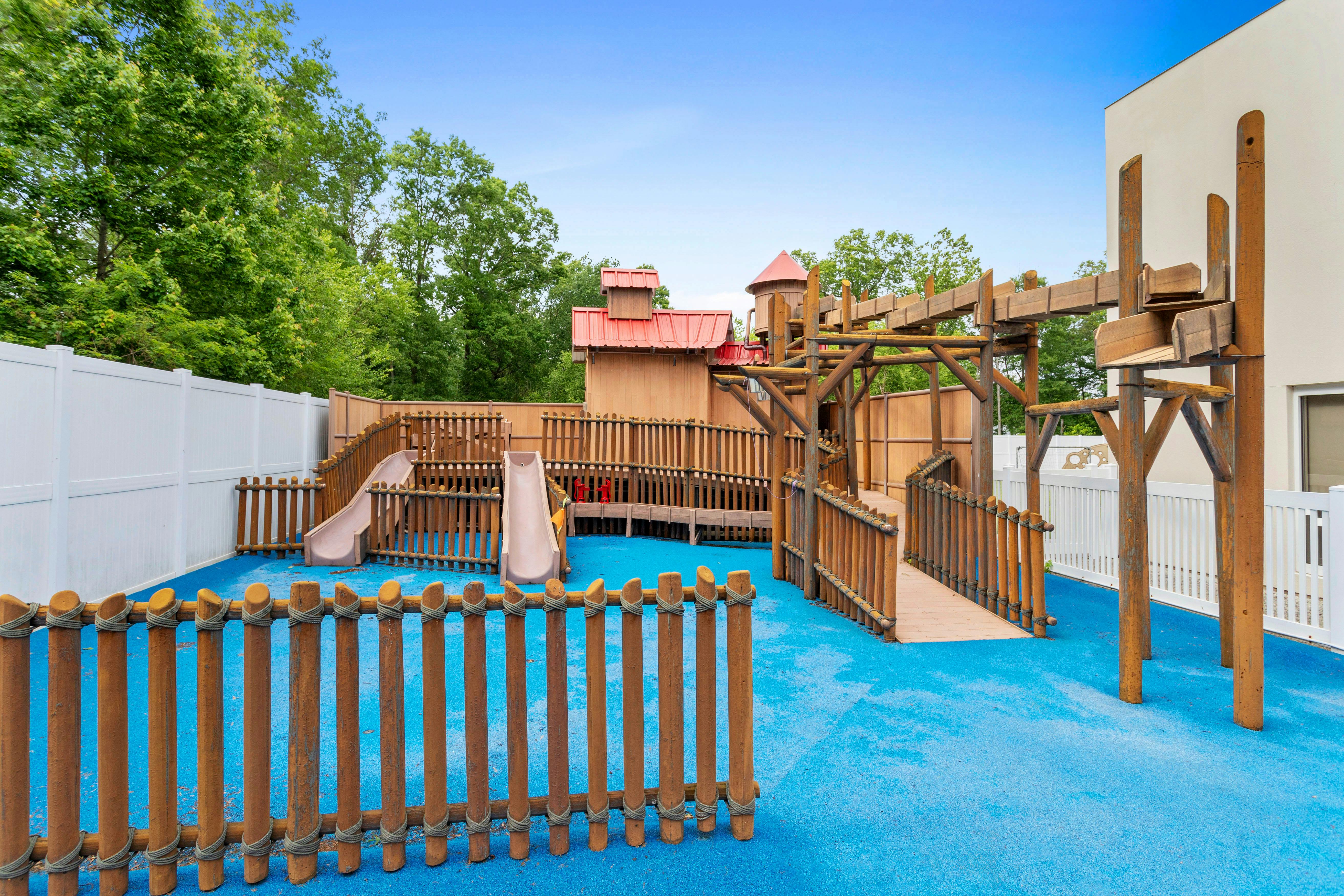 A colorful outdoor playground with slides and wooden structures on blue ground